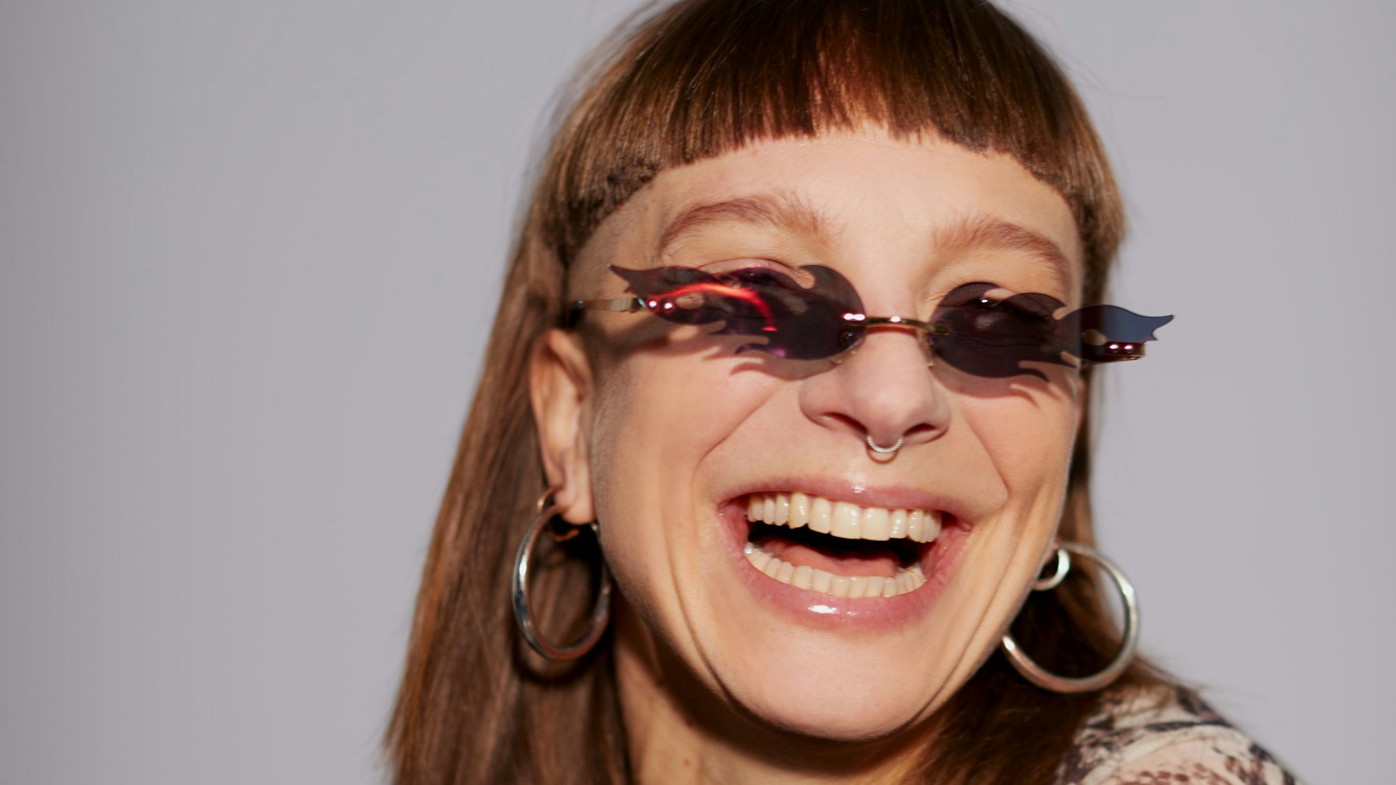 Eine lachende Frau mit einer Sonnenbrille in Flammenform