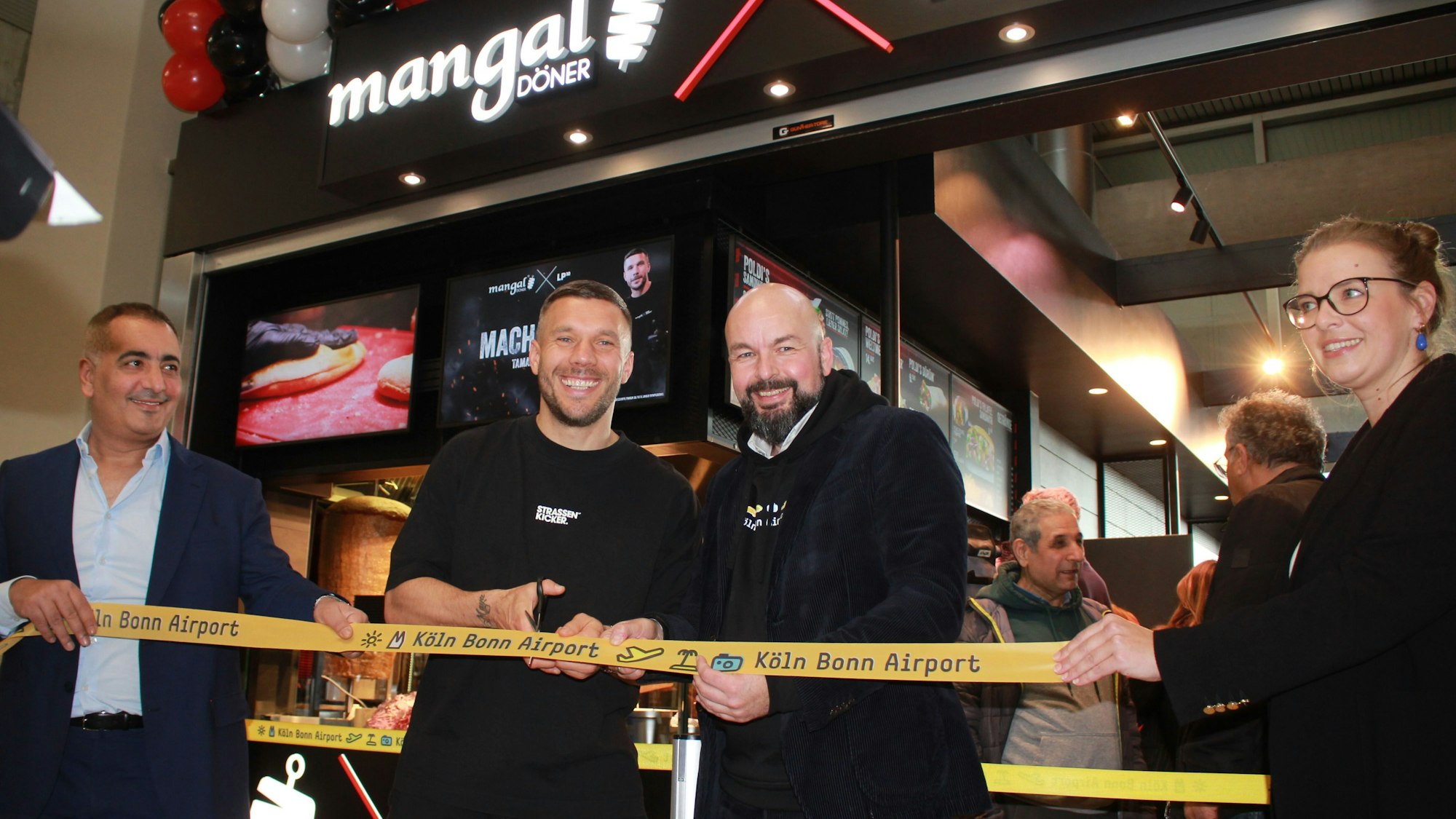 Das Foto zeigt Lukas Podolski bei der Eröffnung der neuen Filiale am Flughafen Köln-Bonn.