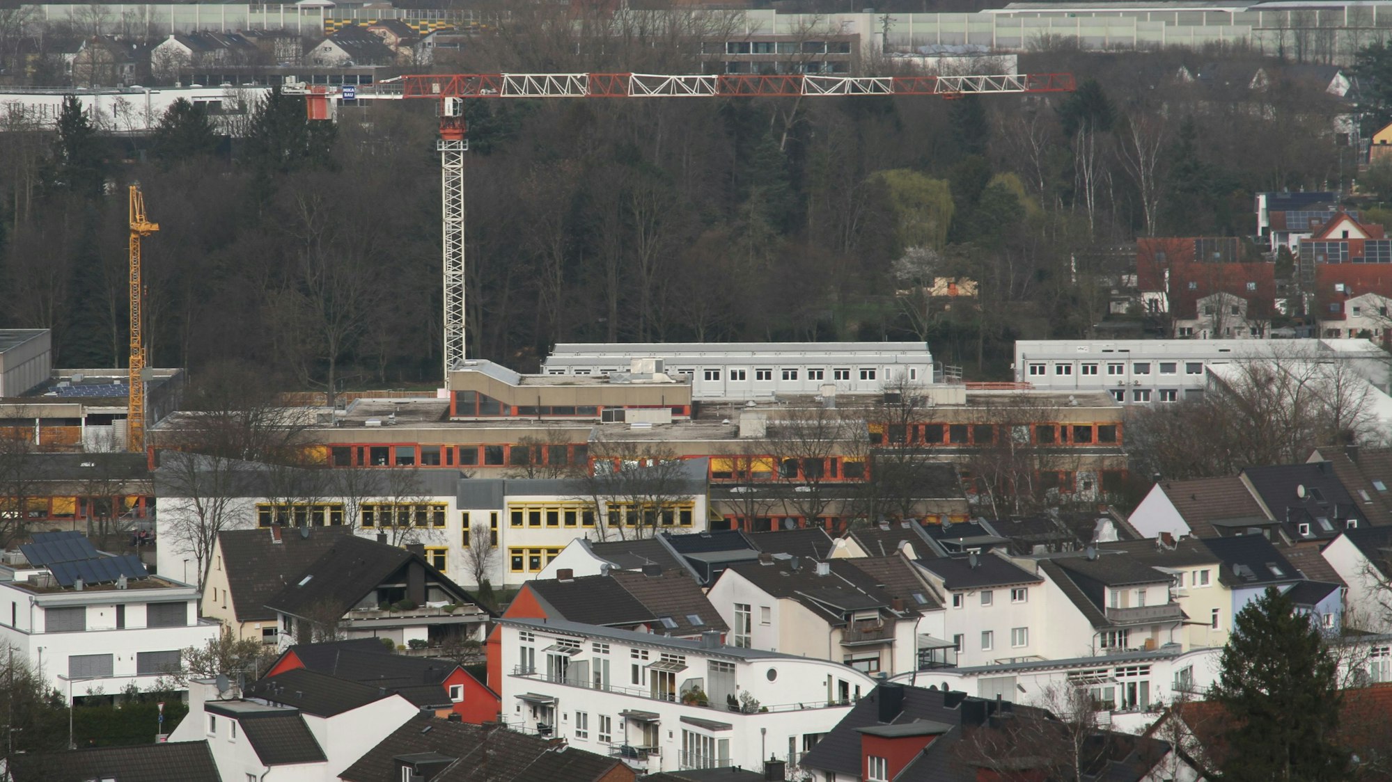 Zwei Baukräne über einem Schulzentrum