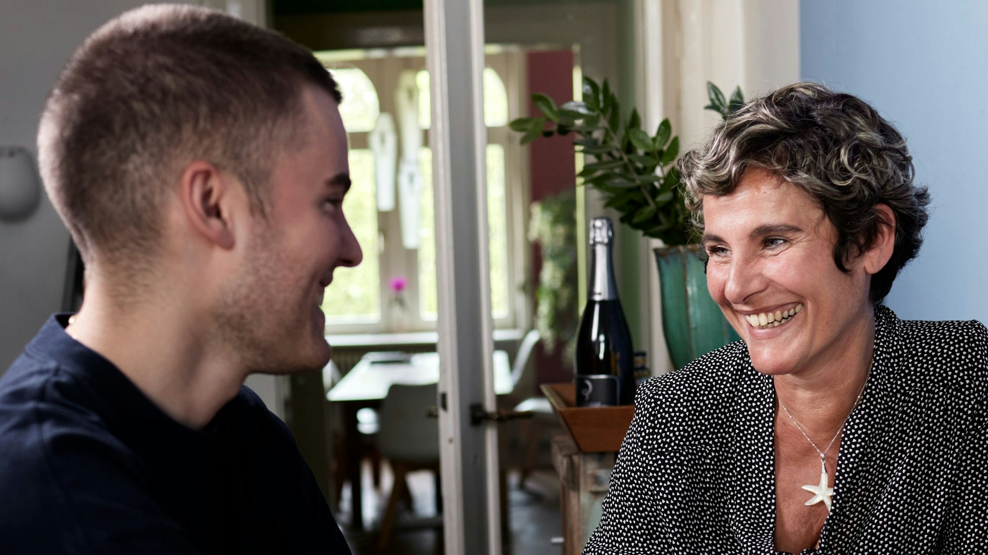 Lächelnde ältere Frau und junger Mann gucken sich an