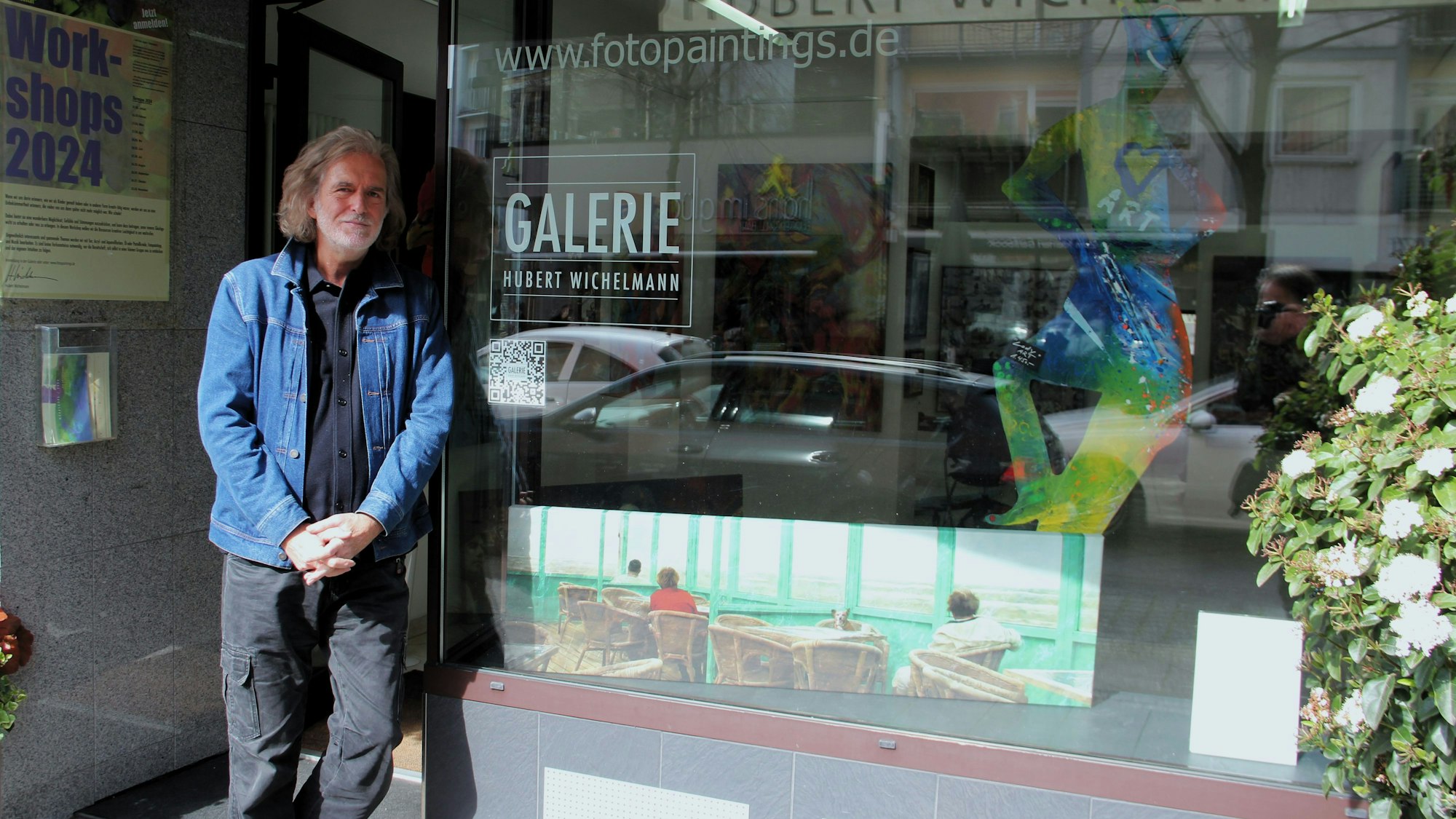 Ein Mann lehnt am Schaufenster seiner Galerie.