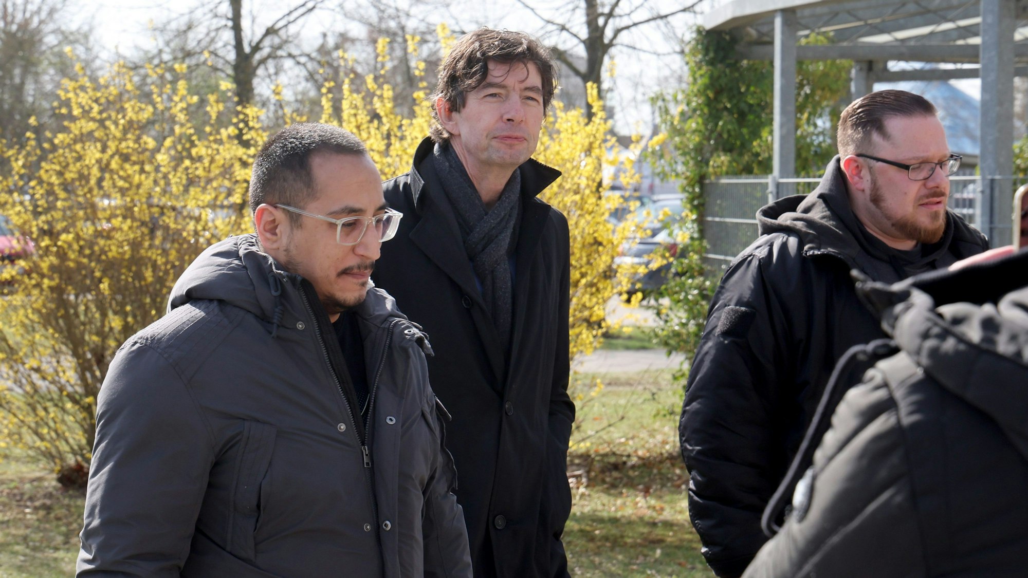 Der Virologe Christian Drosten kommt in Begleitung mehrerer Männer zum Amtsgericht. Am zweiten Prozesstag war er als Zeuge geladen.