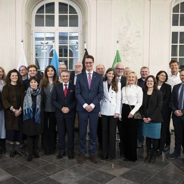 28 Frauen und Männer lächeln in die Kamera, Ministerpräsident Hendrik Wüst überragt sie alle.