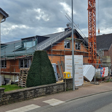 Blick auf einen eingerüsteten Neubau zwischen zwei Bestandsbauten in Kall.
