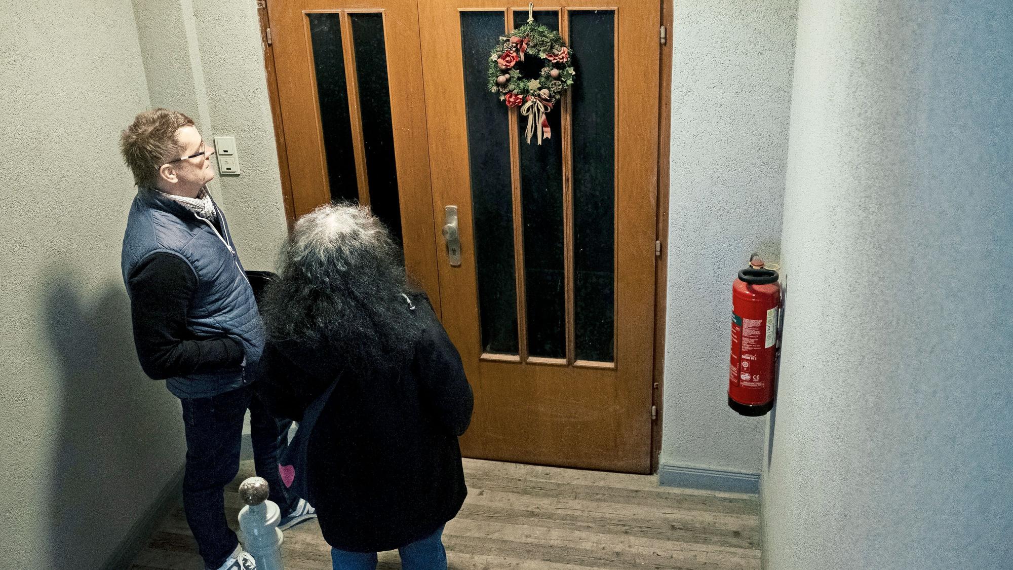 Fatma Edeer-Cetin und Sascha Riepel vom Jobcenter Kassel stehen vor einer Wohnungstür, an der noch im März Weihnachtsschmuck zu sehen ist: ein Hinweis darauf, dass die gesuchte Person möglicherweise ausgezogen ist.
(Foto: Jonas Dengler)