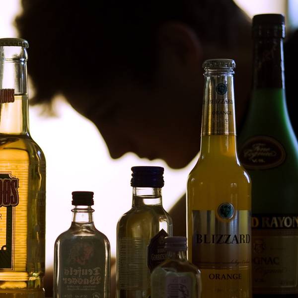 ARCHIV - ILLUSTRATION - Ein Jugendlicher sitzt hinter Flaschen mit Alkohol.