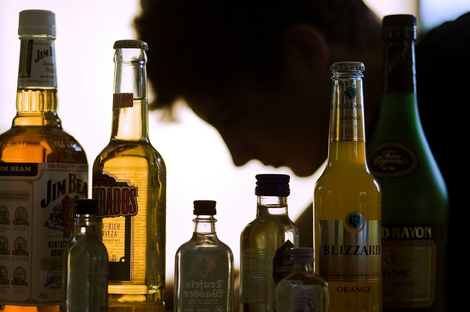 Ein Jugendlicher sitzt hinter Flaschen mit Alkohol,