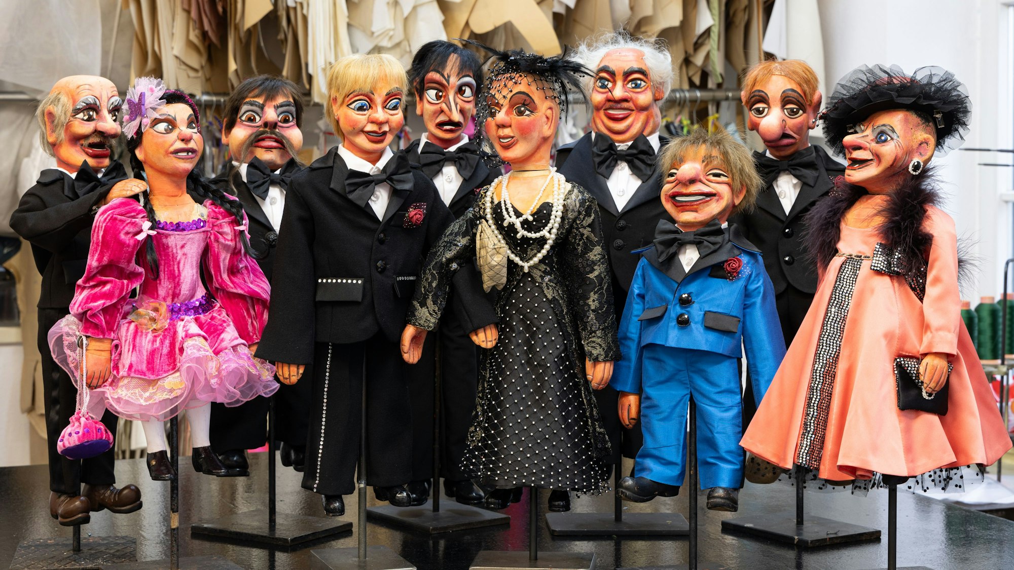 Hänneschen-Puppen stehen in Abendgarderobe beisammen.