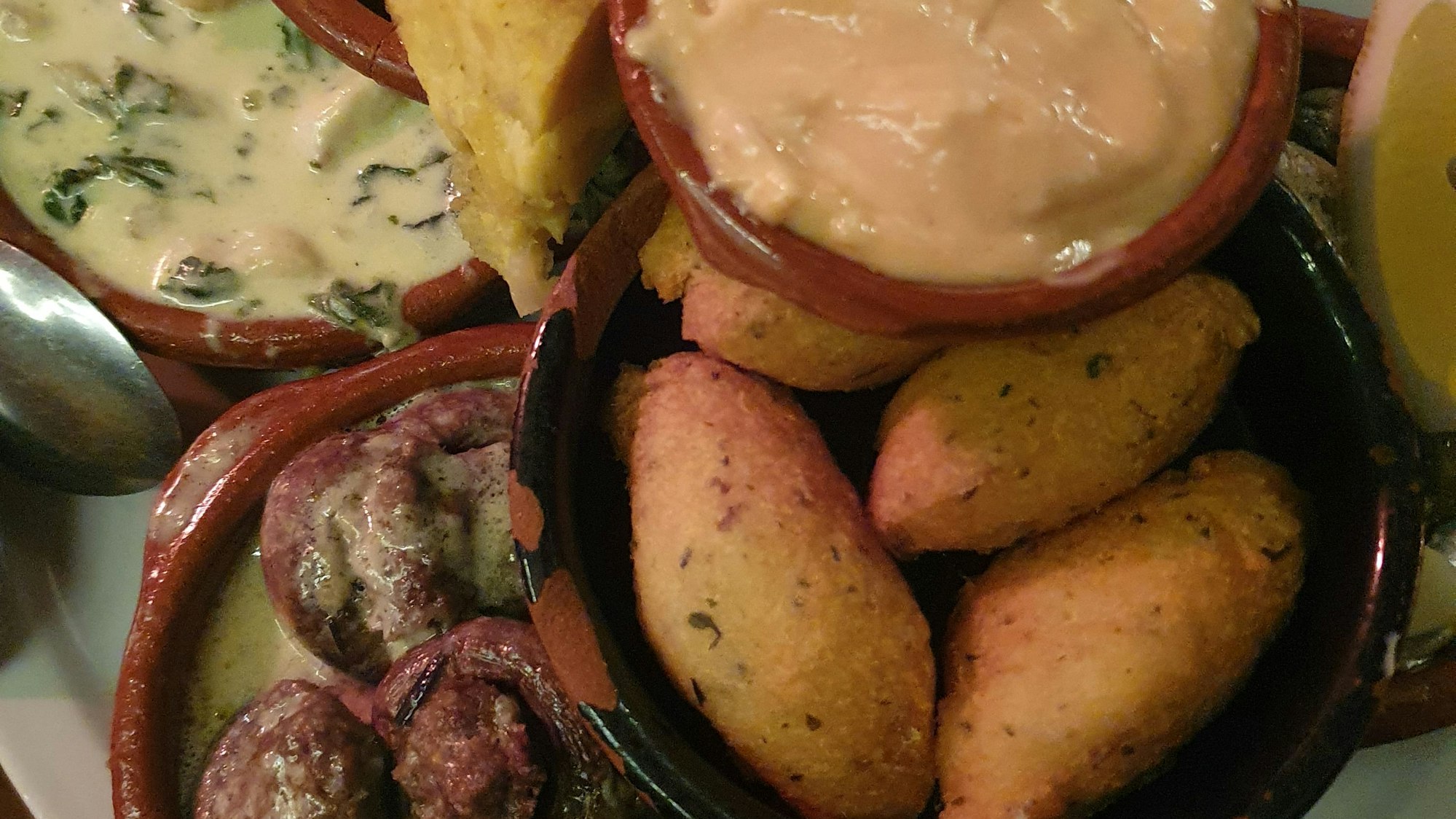 Eine Auswahl Tapas in den typischen Schälchen, zum Beispiel Aioli und gefüllte Champignons.