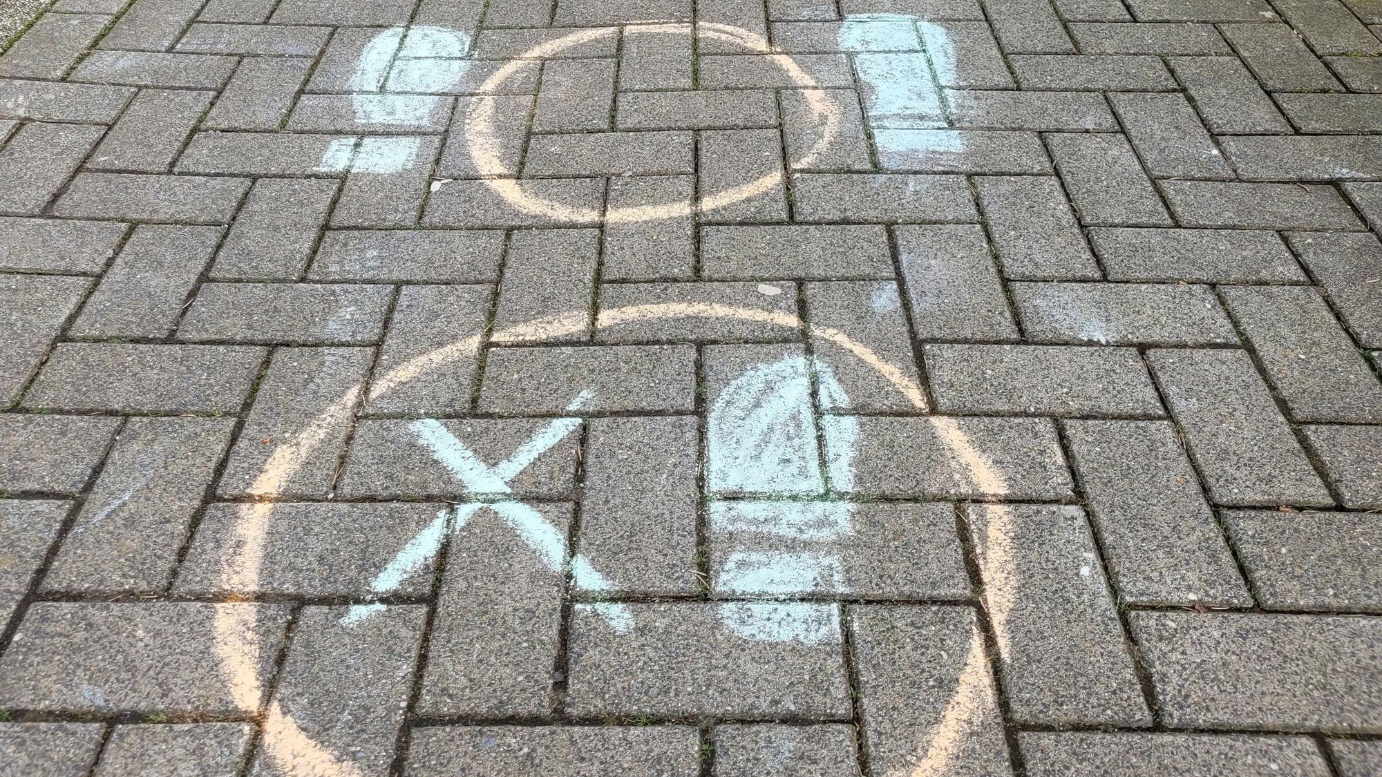 Hüpfspiele aus kunterbunter Kreide finden sich zurzeit auf dem Pflaster des Gehwegs an der Schillerstraße in der Stadtmitte von Waldbröl. Hier zu sehen sind zwei Hüpfkreise.