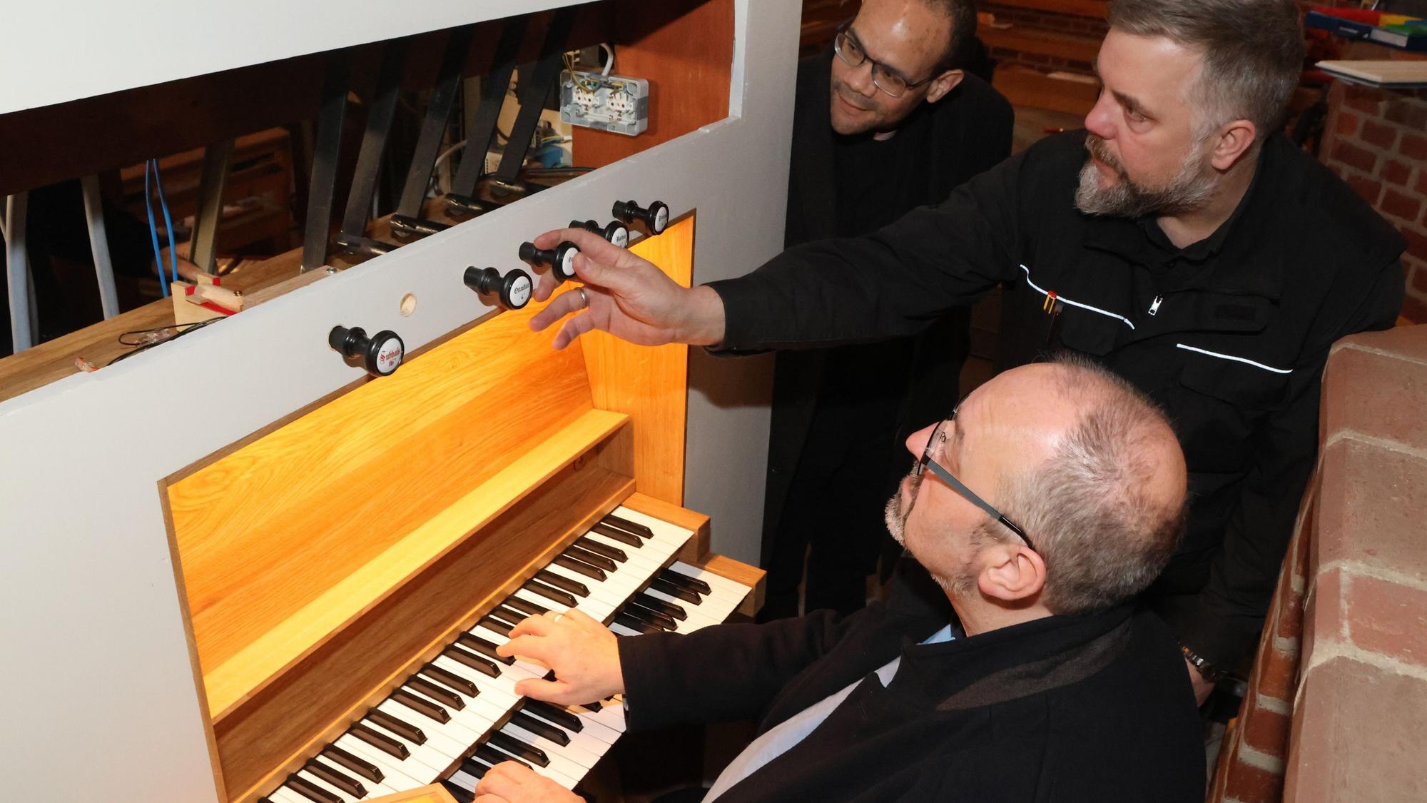 Martin Hiltmann (Mite) erklärt Dr. Dirk van Betteray (sitzend) und Pastor Tobias Zöller die neue Orgel.