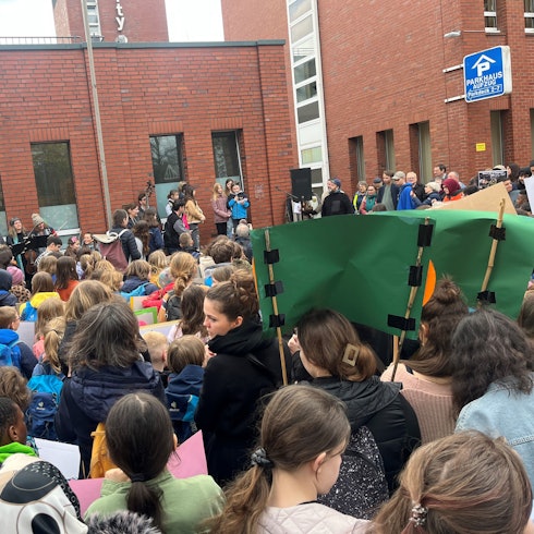 Eine Menschenmasse, bestehend aus Kindern, hält Plakate hoch.