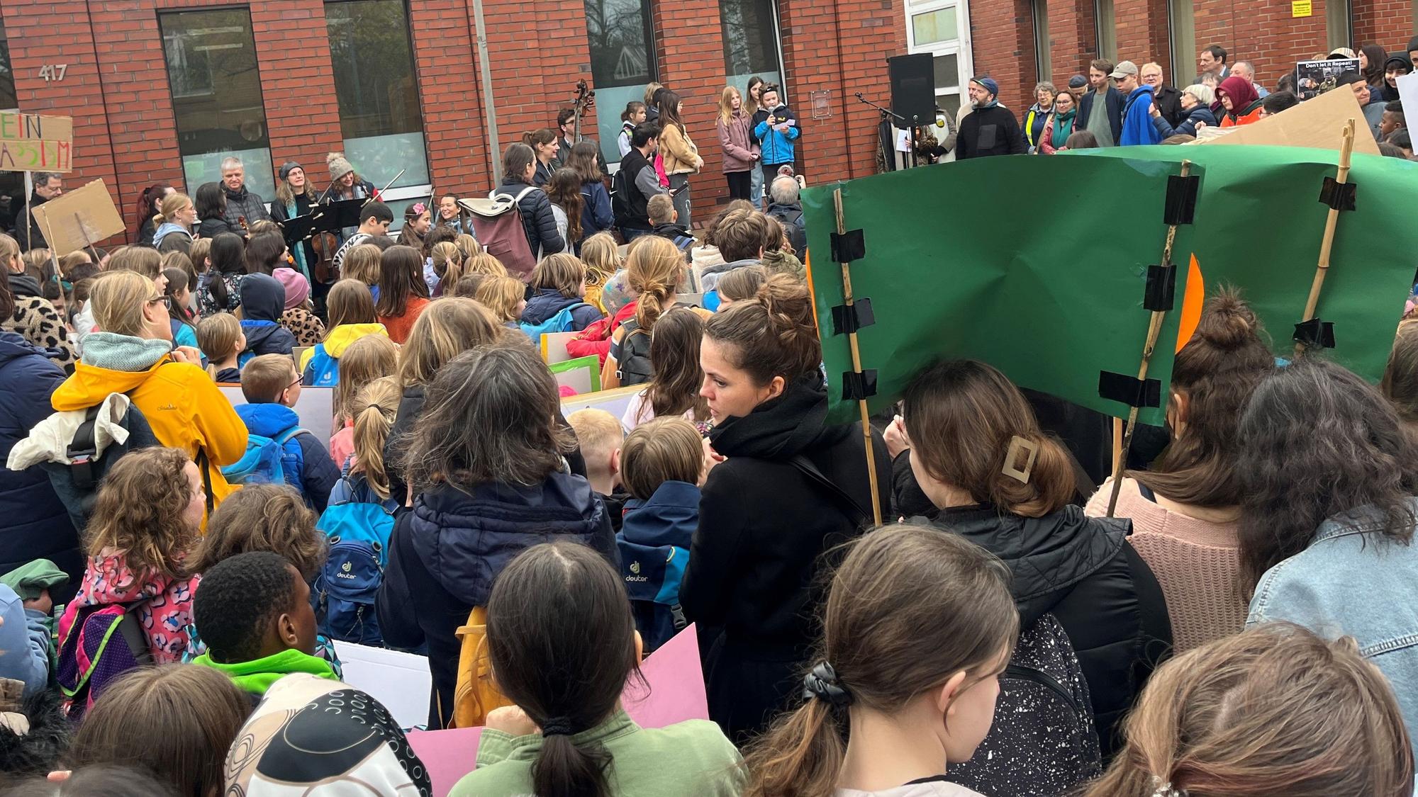 Eine Menschenmasse, bestehend aus Kindern, hält Plakate hoch.