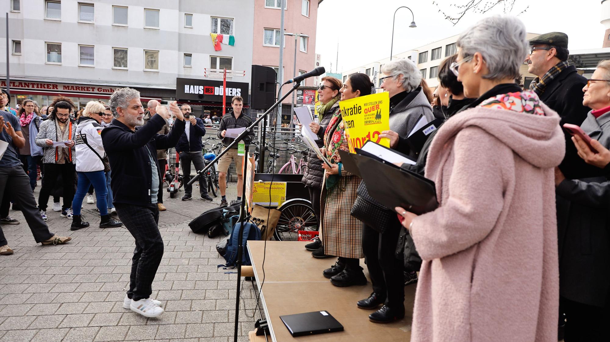 Menschen bei einer Demonstration stehen auf einer Bühne vor einem Mikrofon.