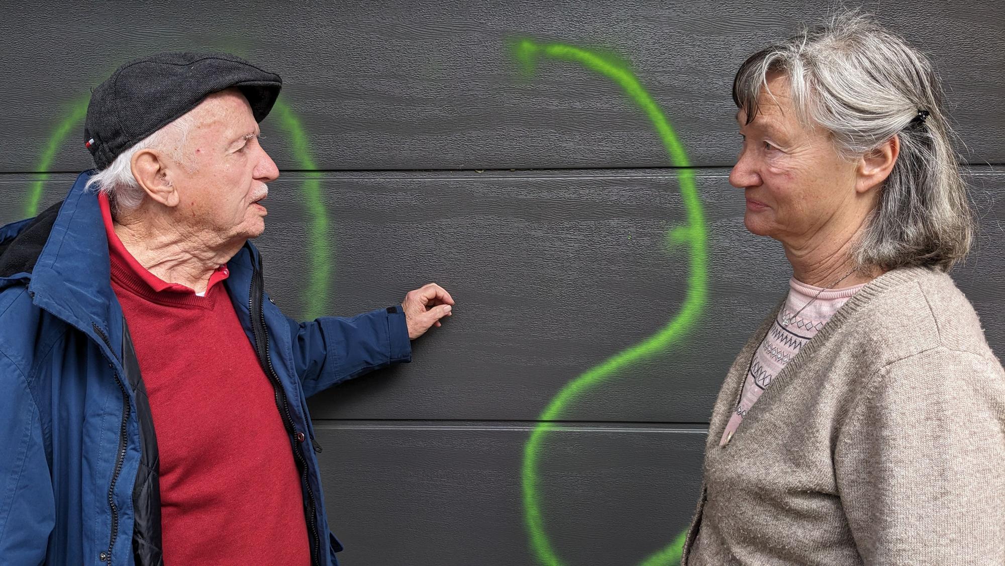 Peter und Rosemarie Leister aus Bad Münstereifel-Mahlberg stehen fassungslos vor ihrem Garagentor, das mit grüner Signalfarbe beschmiert worden ist.