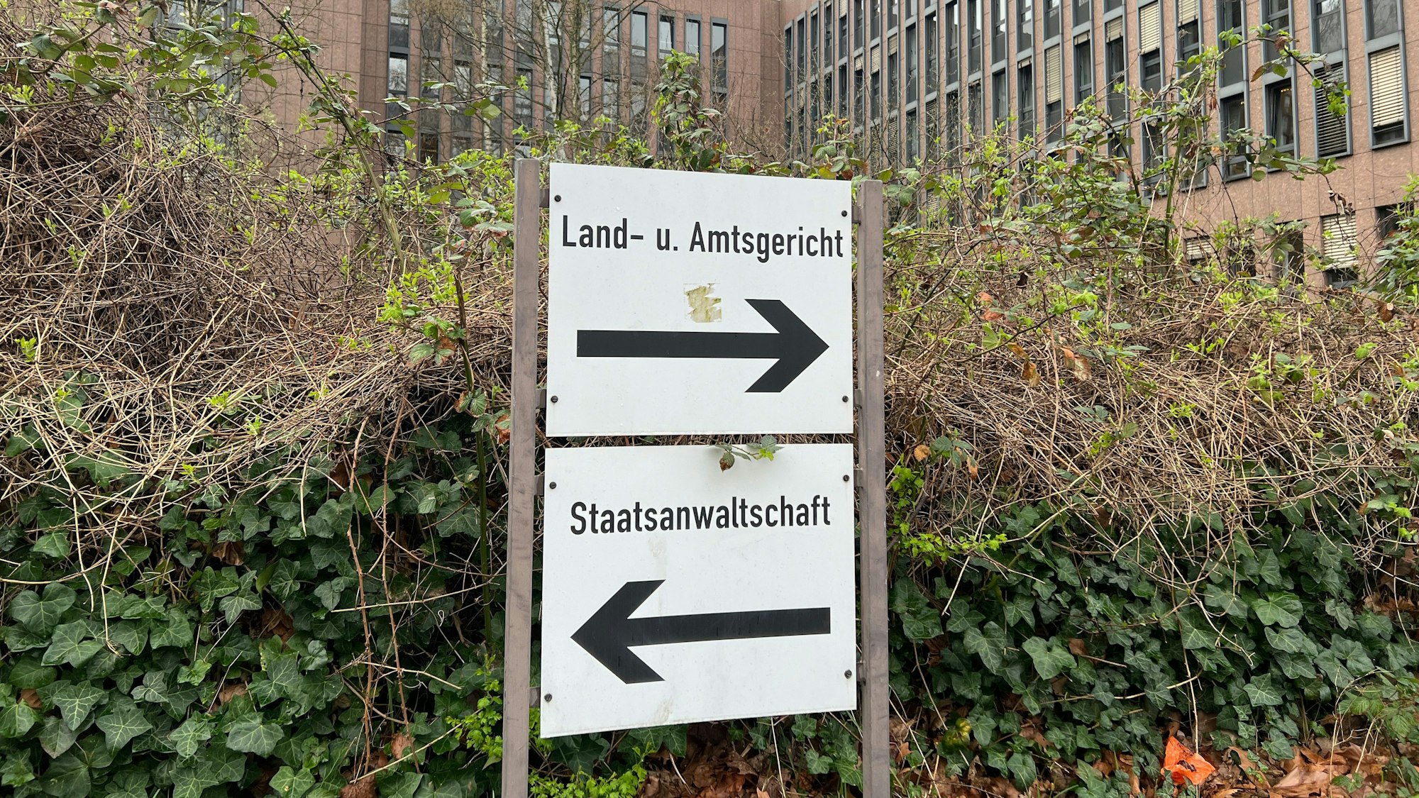 Auf dem Foto ist ein Schild vor dem Kölner Gerichtszentrum zu sehen, das auf das Land- und Amtsgericht sowie die Staatsanwaltschaft hinweist.