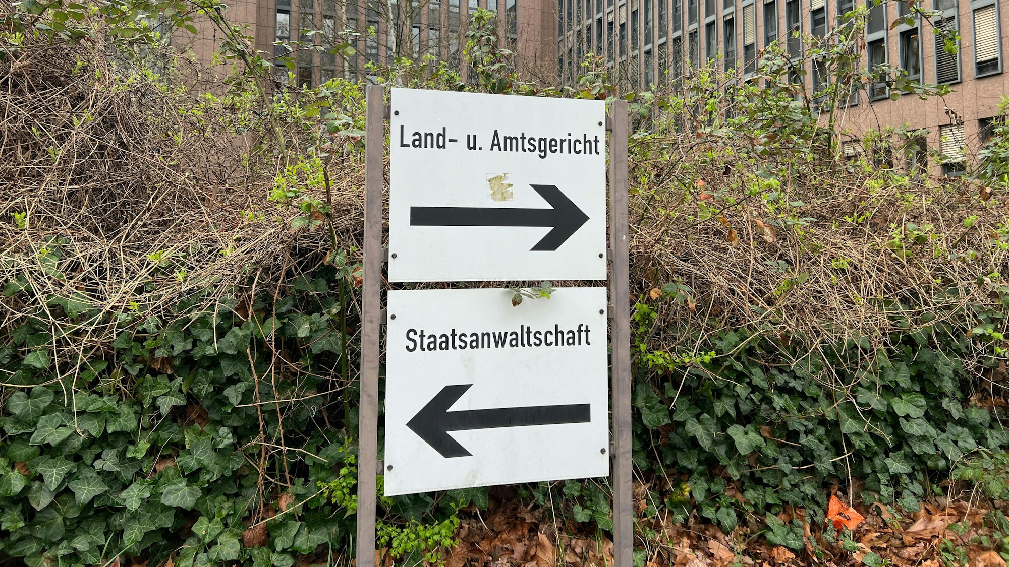 Auf dem Foto sind Schilder zu sehen,, die zum Land- und Amtsgericht Köln und zur Staatsanwaltschaft weisen. Im Hintergrund ist das Gerichtsgebäude zu suchen.