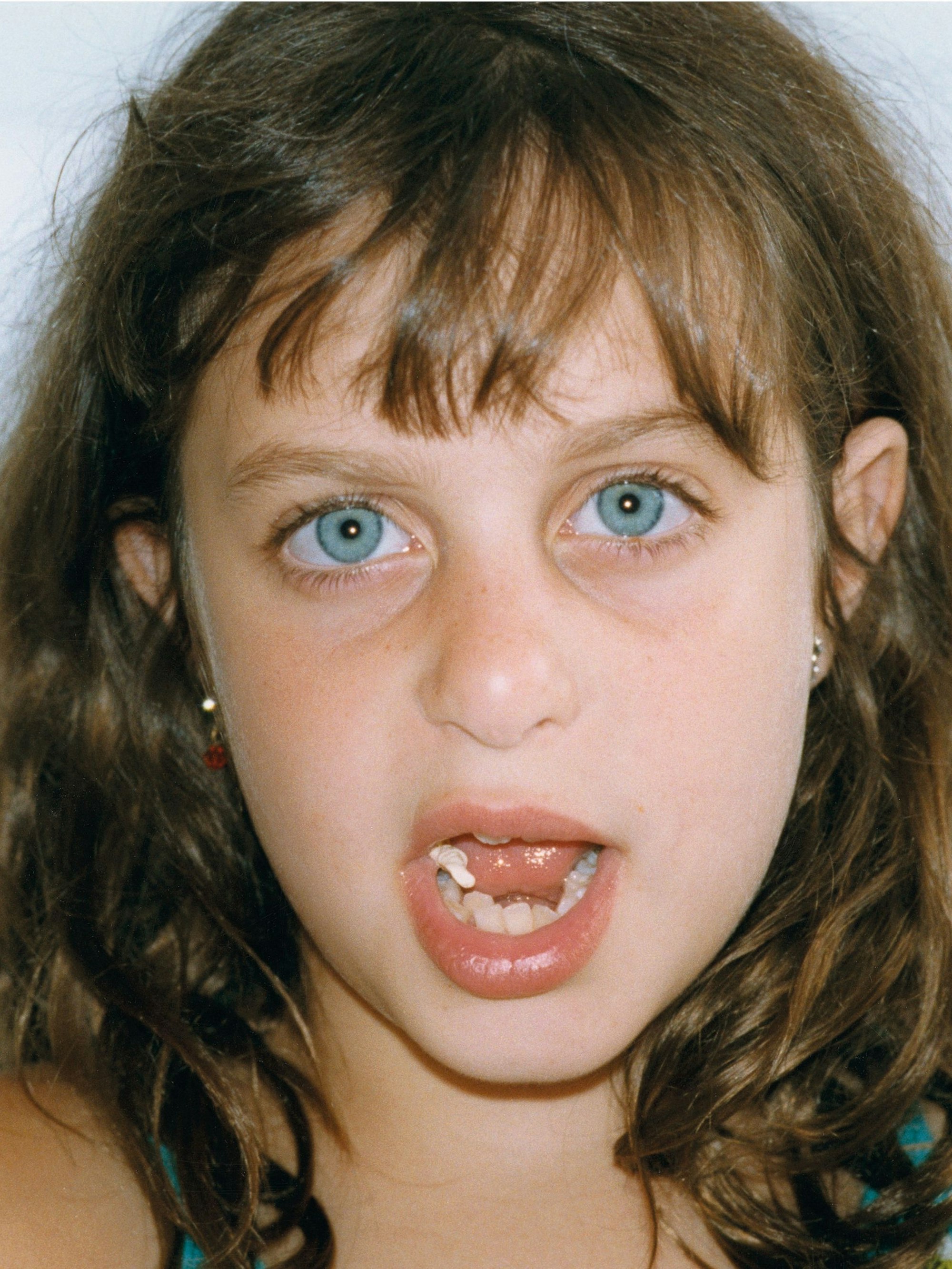 Ein junges Mädchen kaut Gummi mit offenem Mund.