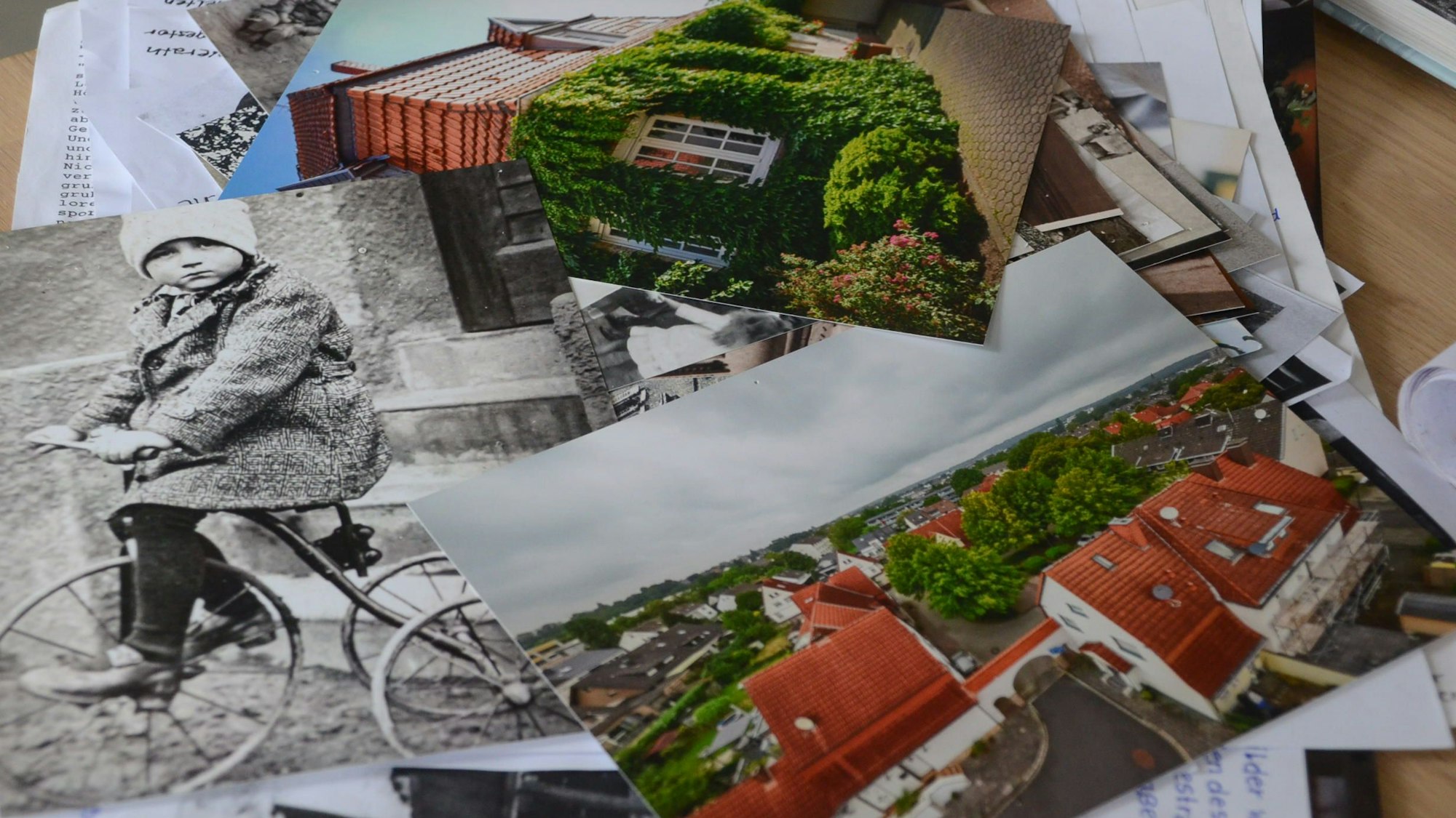 Schwarz-Weiß-Fotos und farbige Aufnahmen liegen auf einem Tisch.