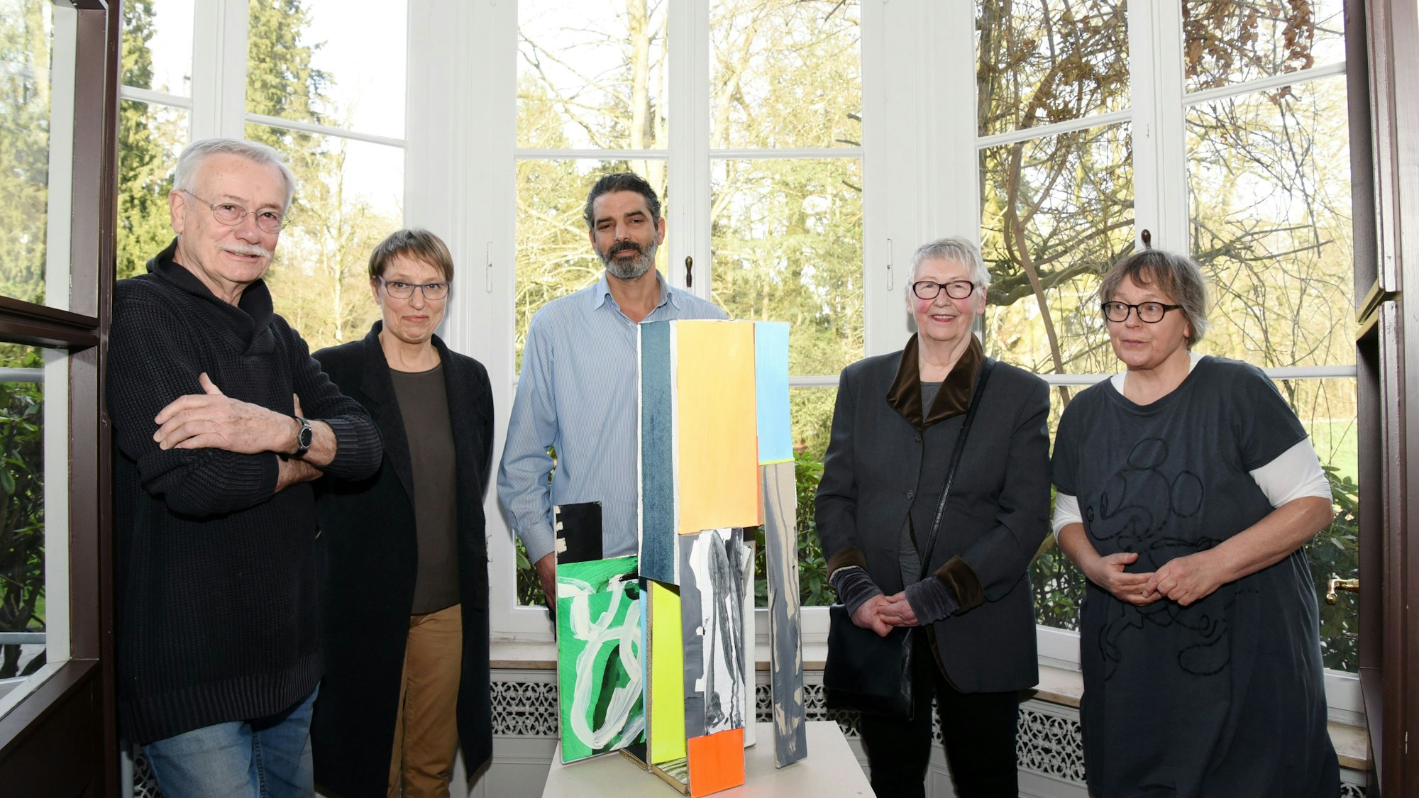 Eine Gruppe steht im Halbkreis um ein Kunstobjekt.