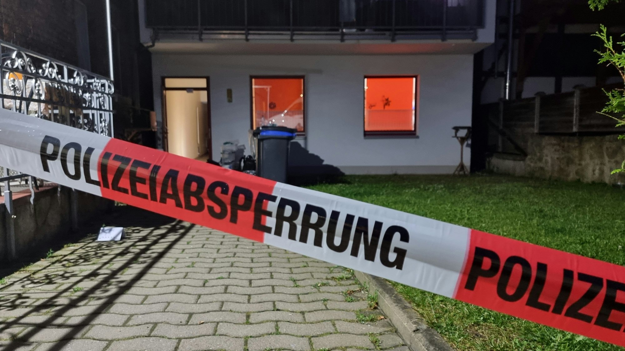 Blick auf die Rückseite eines Hauses mit einem Absperrband der Polizei davor.