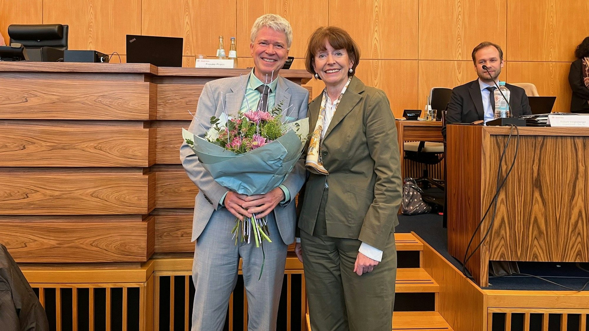 Harald Rau erhält steht mit einem Blumenstrauß neben Oberbürgermeisterin Henriette Reker.