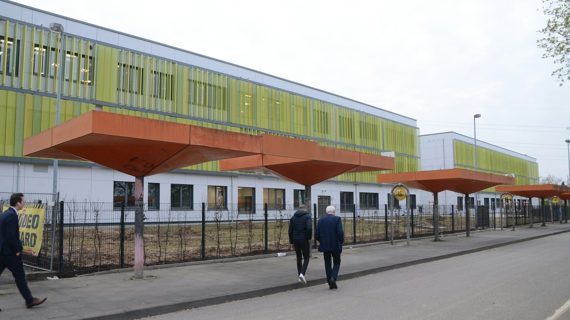 Fußgänger gehen auf einem Bürgersteig neben der Gertrud-Koch-Gesamtschule.