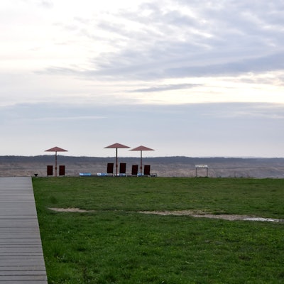 Ein Holzsteg führt zu einem Tagebaurand.
