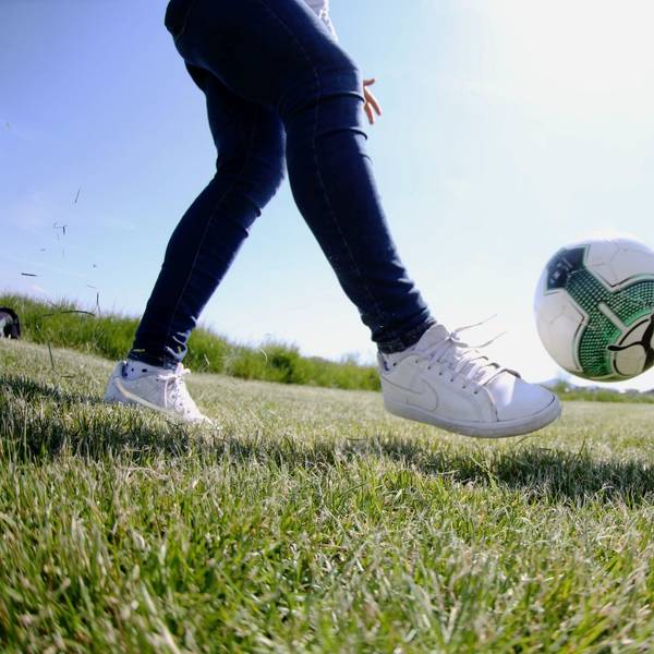 Eine Frau schießt einen Ball Richtung eines Ziels.