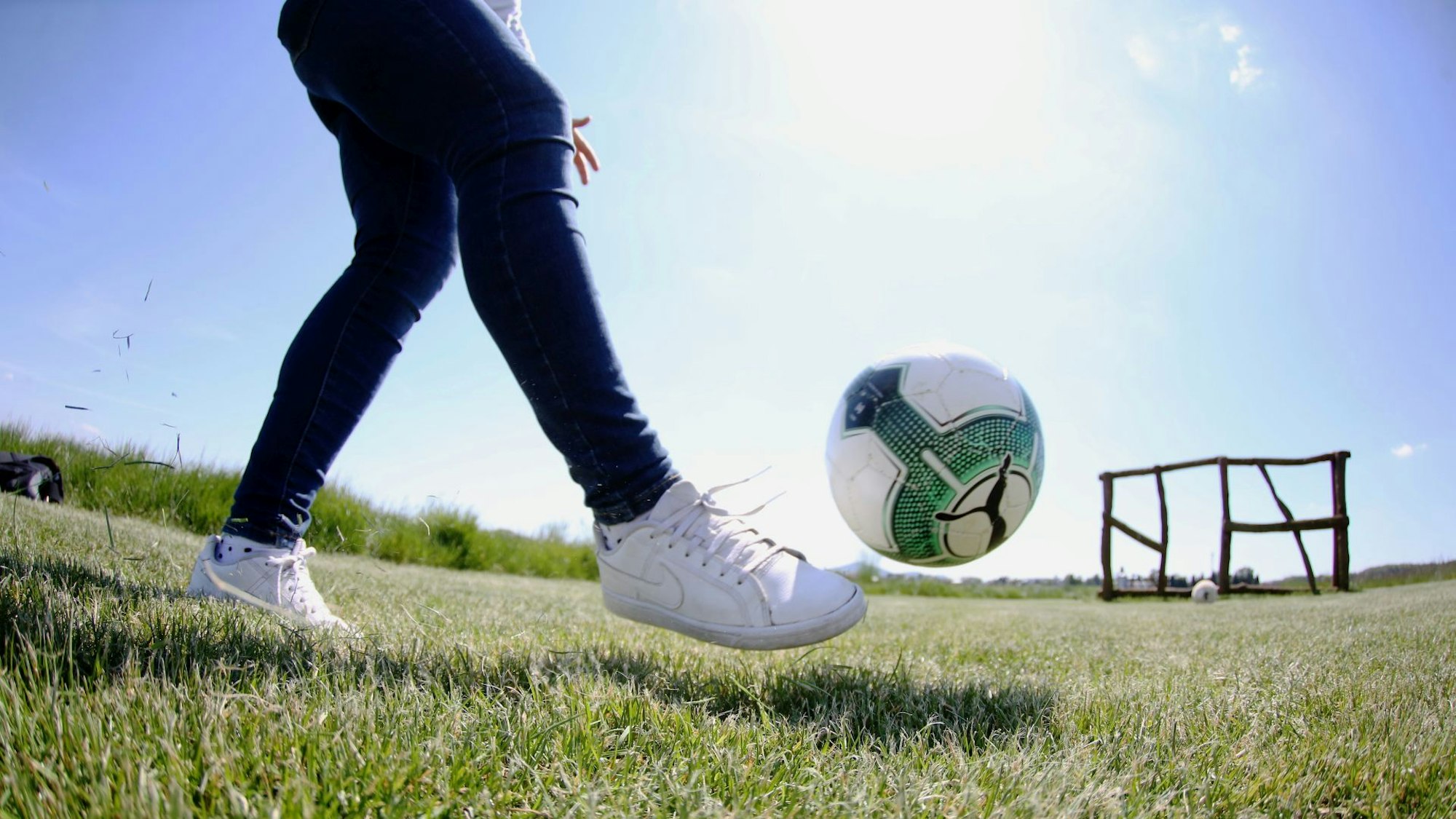 Eine Frau schießt einen Ball Richtung eines Ziels.