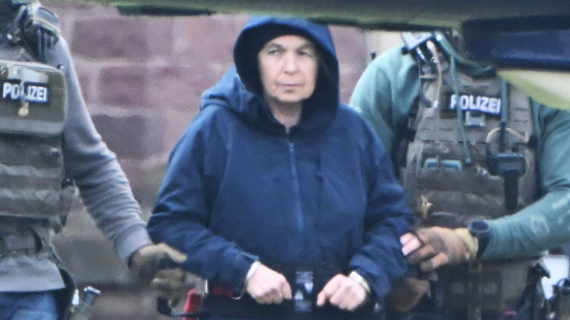 Im Innenhof eines Behördenzentrums wird die frühere RAF-Terroristin Daniela Klette zu einem Hubschrauber geführt. (Archivbild)dpa