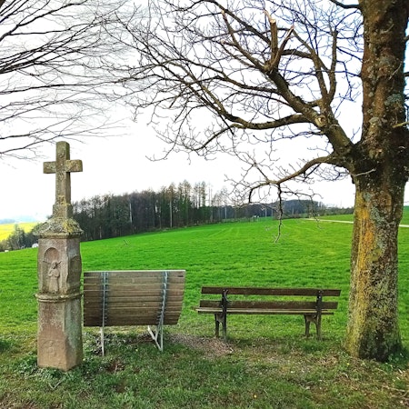 Ein Wegekreuz vor Panoramablick.