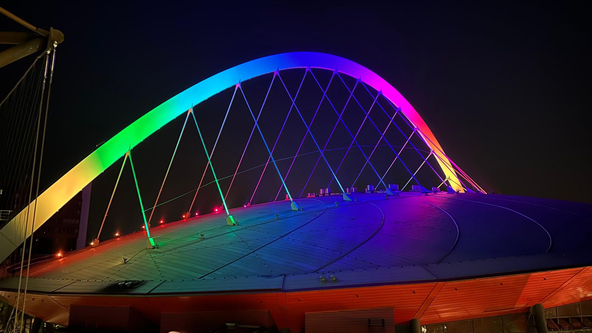 Der bunt beleuchtete Rundbogen der Arena bei Nacht