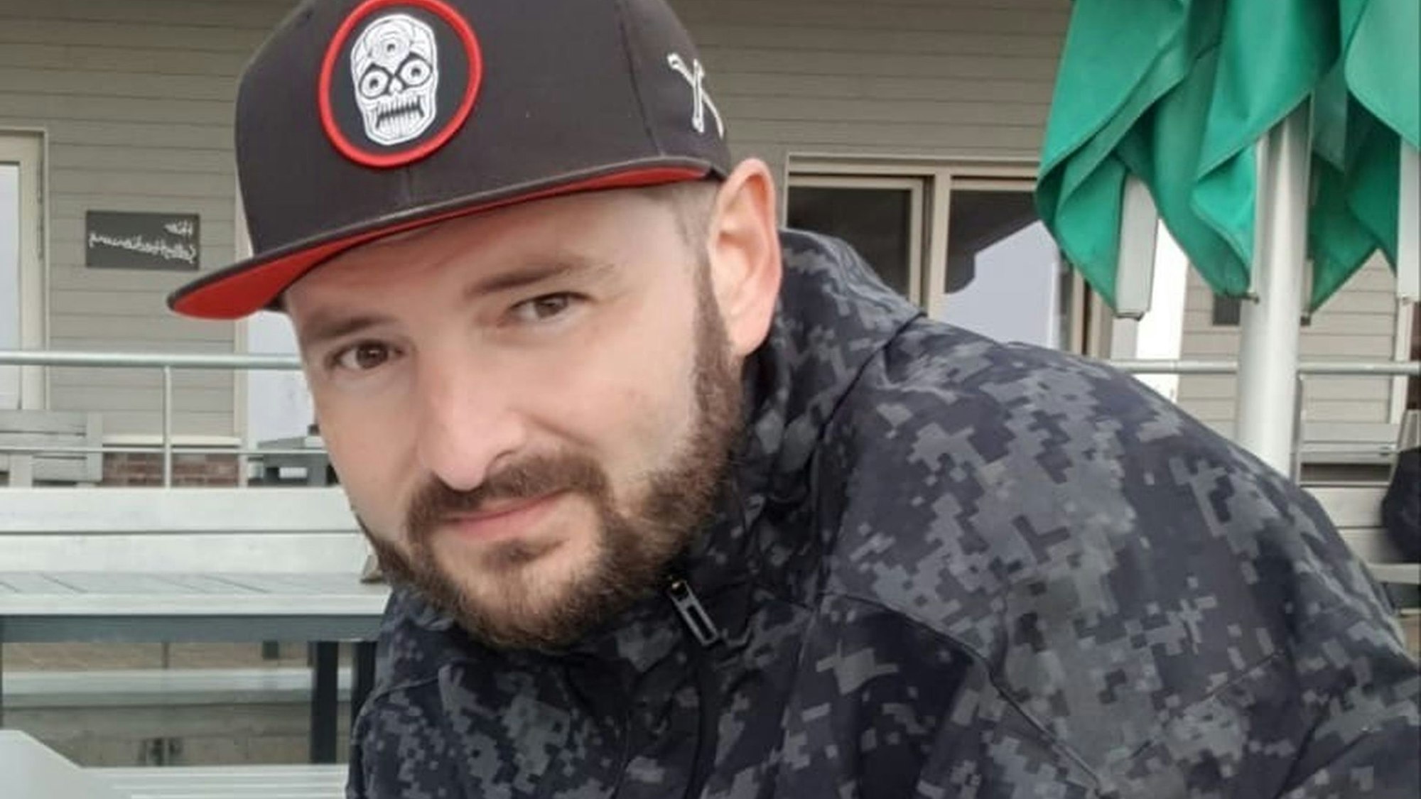 Ein Mann mit Bart und Käppi schmunzelt in die Kamera.