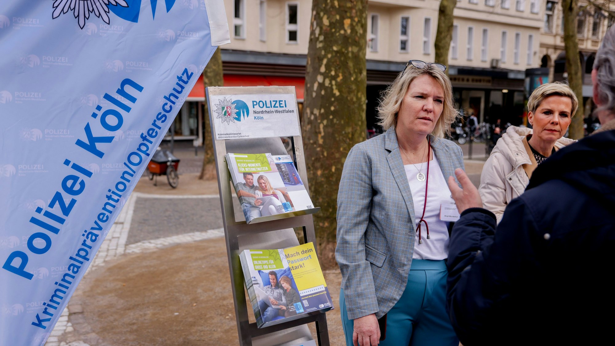 Das Foto zeigt Birgit Wunderlich (Opferschutz des Landes NRW) (links) und Anja Kleck (Kriminalprävention / Opferschutz Polizei Köln) im Gespräch mit einem Passanten.
