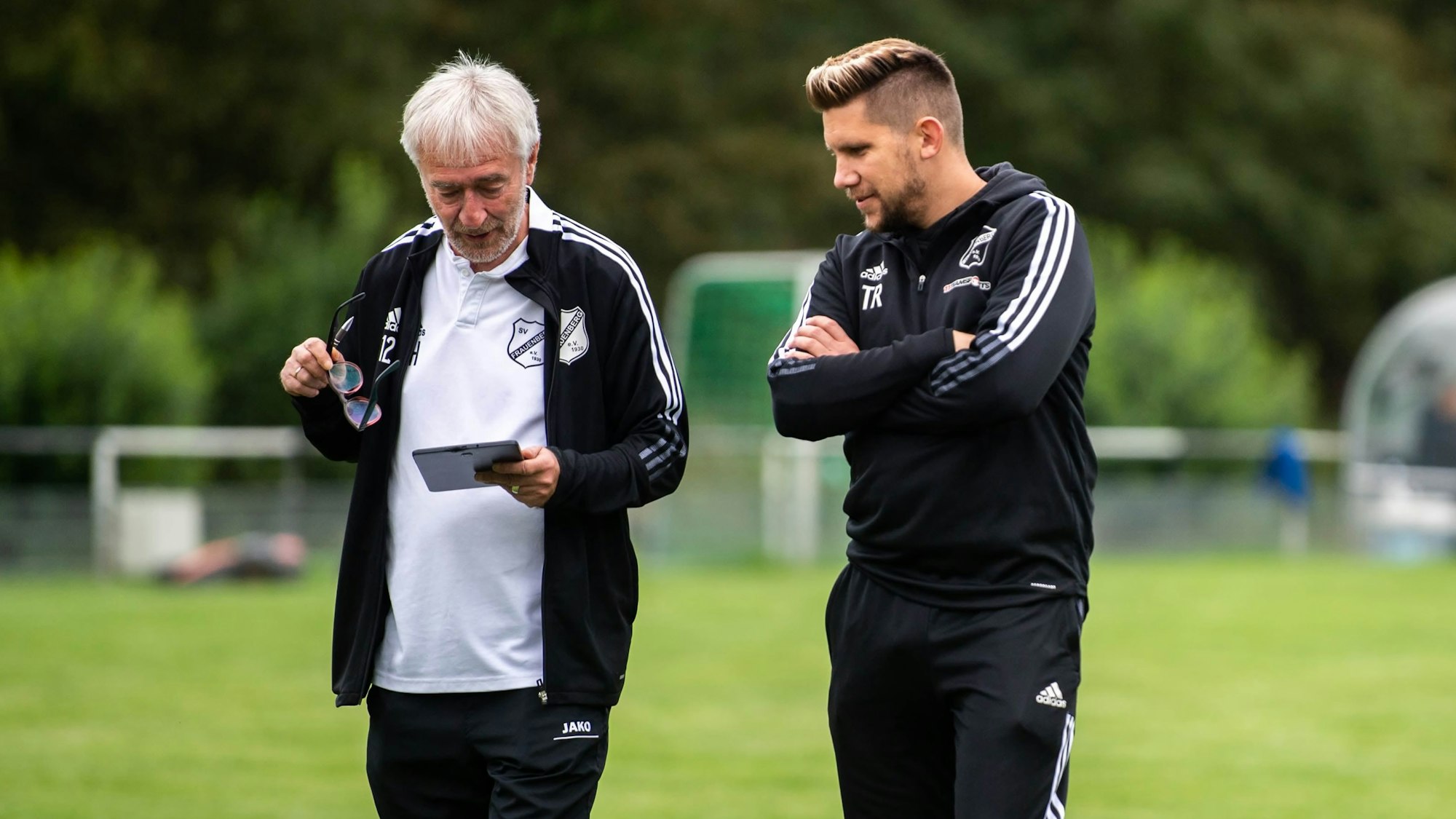 Motz und Kaiser schauen sich auf einem Tablet die Aufstellung des Gegners an.