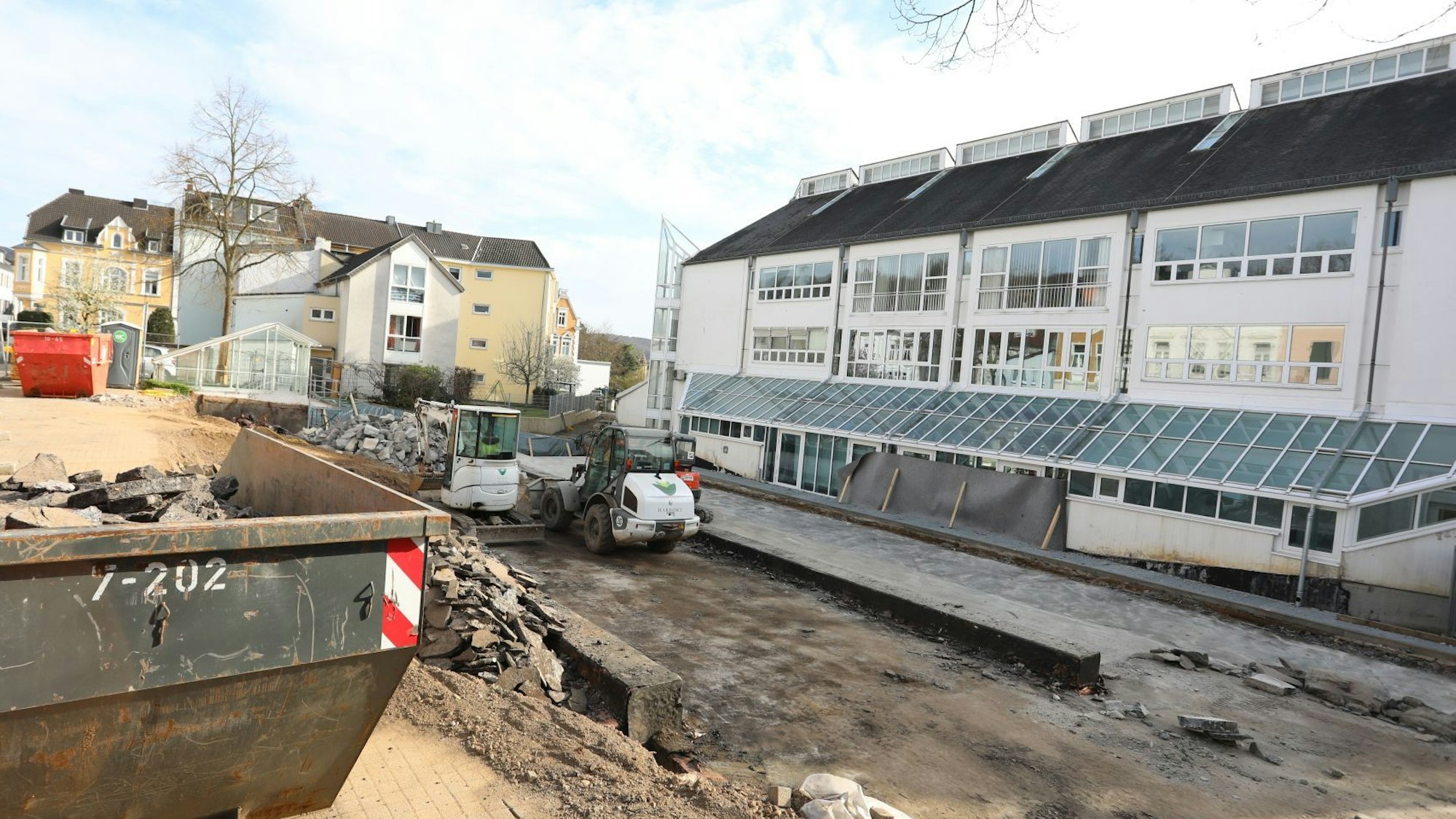 Ein Baucontainer und Maschinen stehen in einer Baustelle neben dem Rathaus.