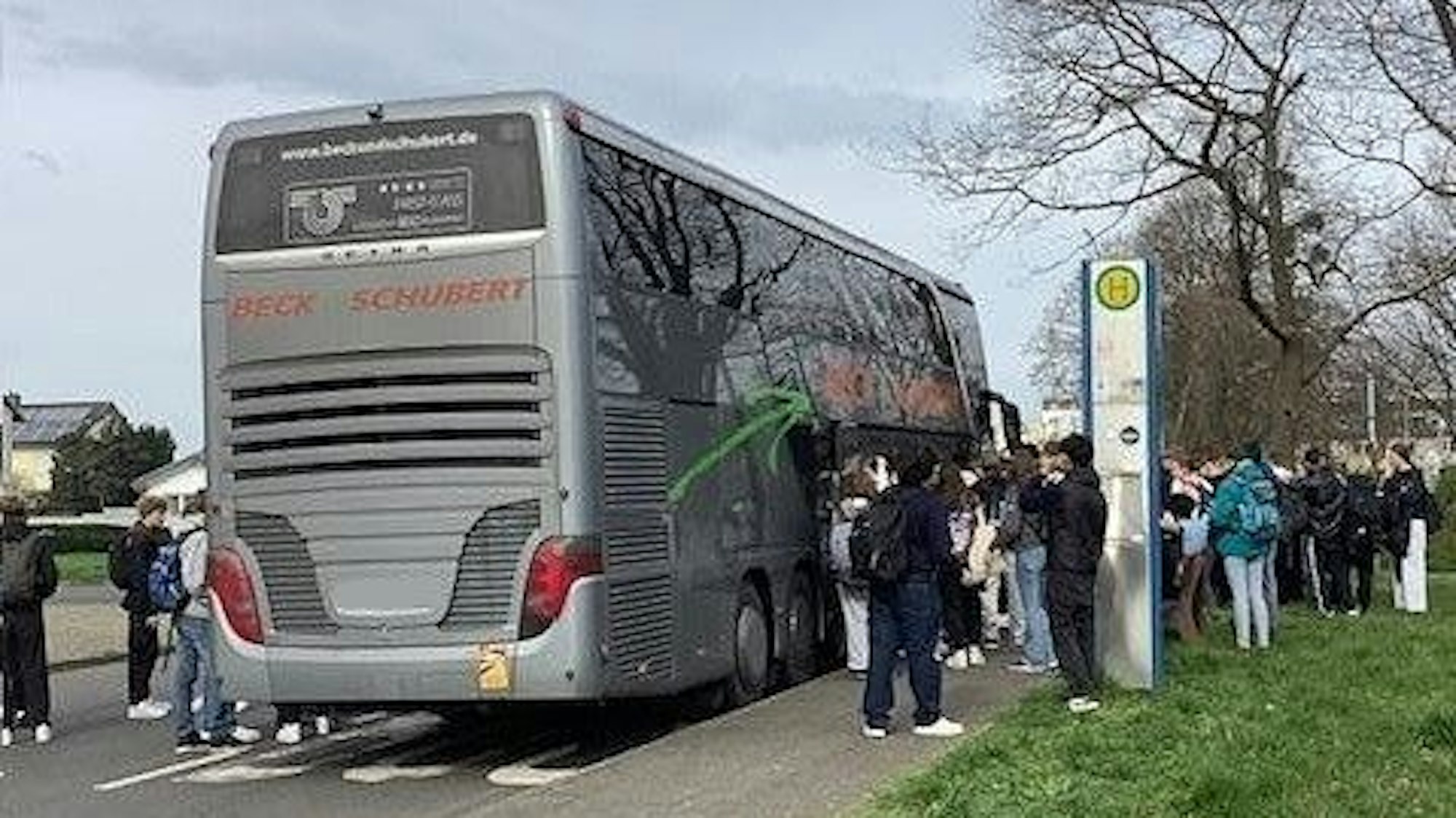 Auf dem Foto sind wartende Schüler vor einem Reisebus zu sehen.