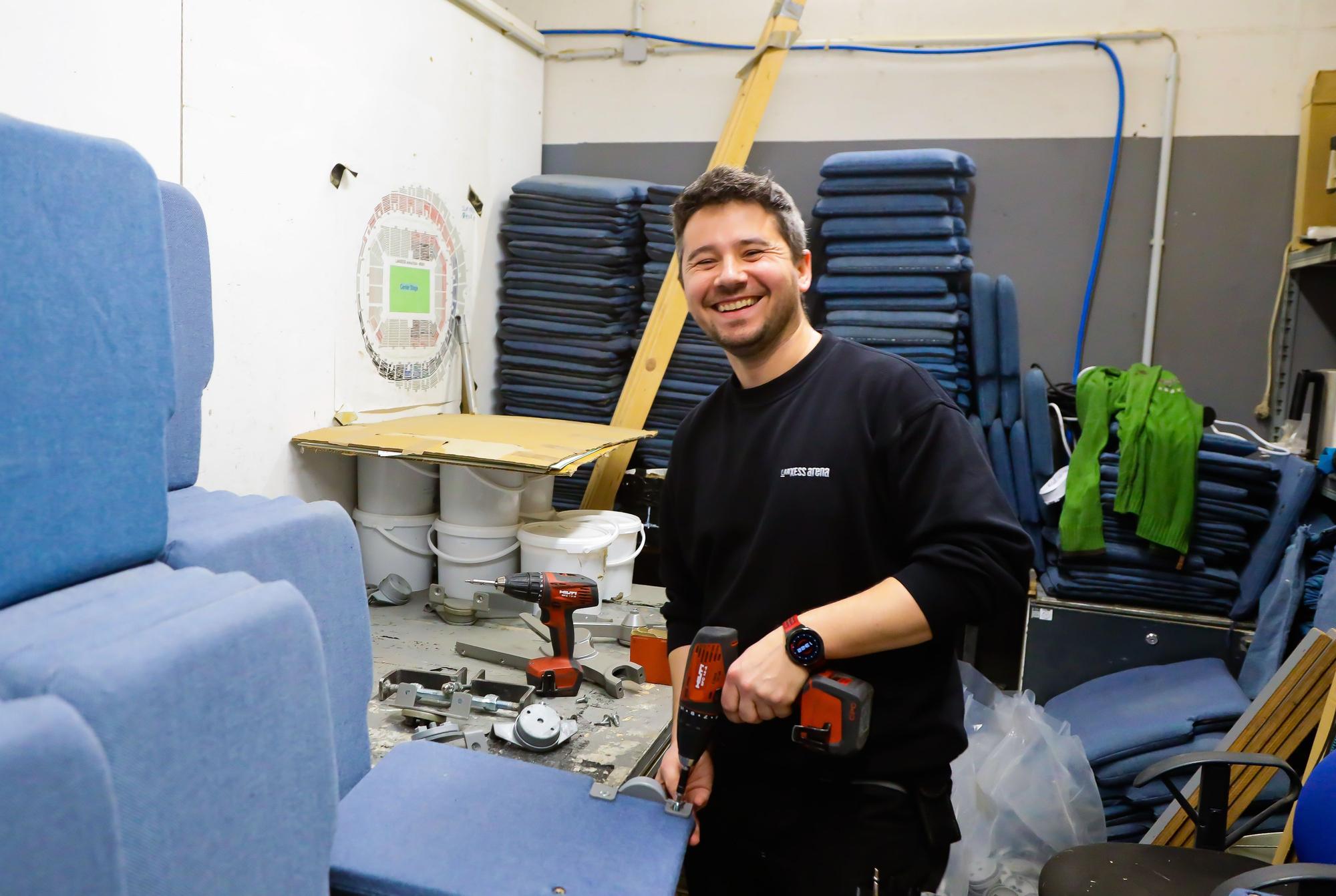 Marek Bienkowski hat einen Akku-Schrauber in der Hand und repariert einen Stuhl.