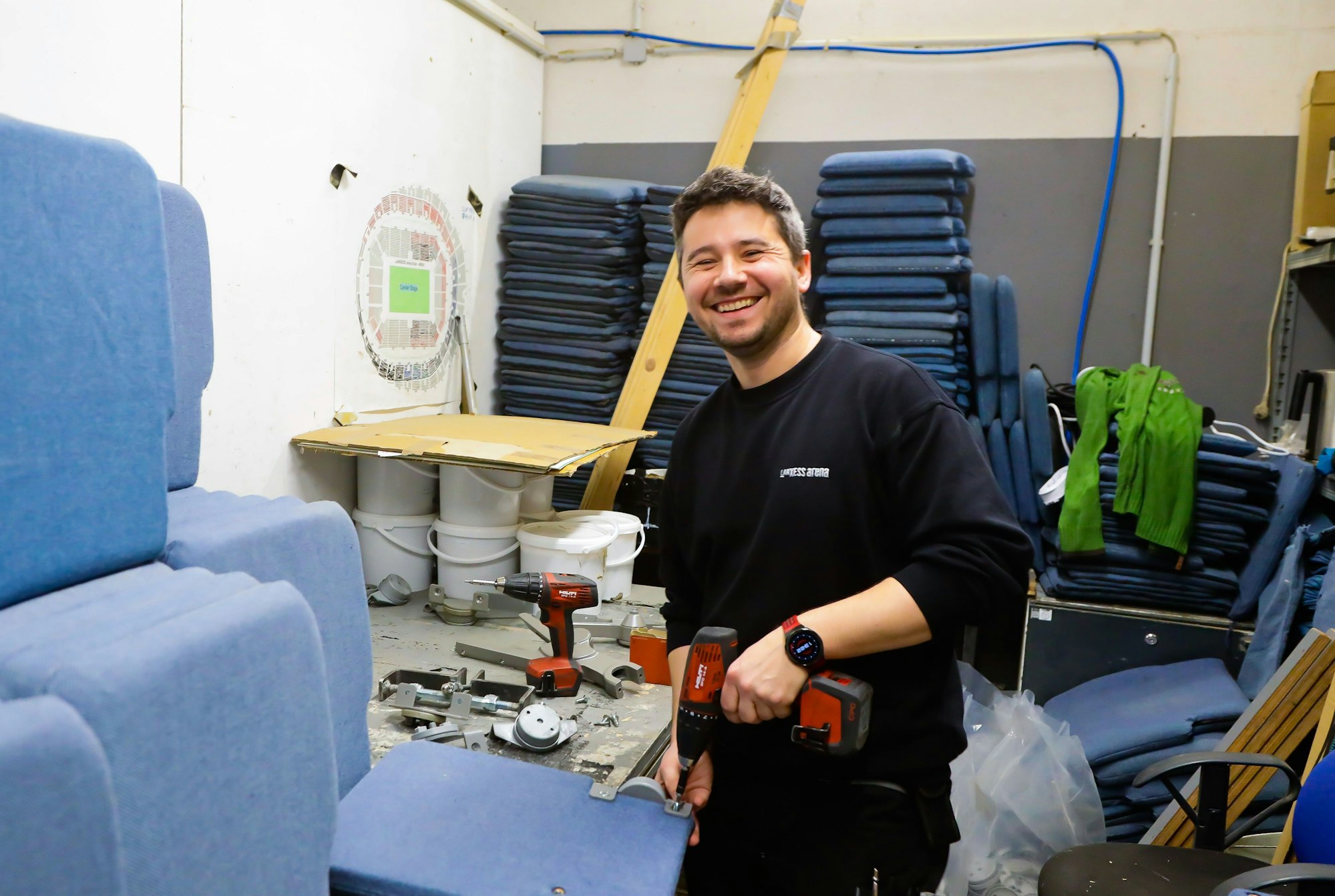 Marek Bienkowski hat einen Akku-Schrauber in der Hand und repariert einen Stuhl.