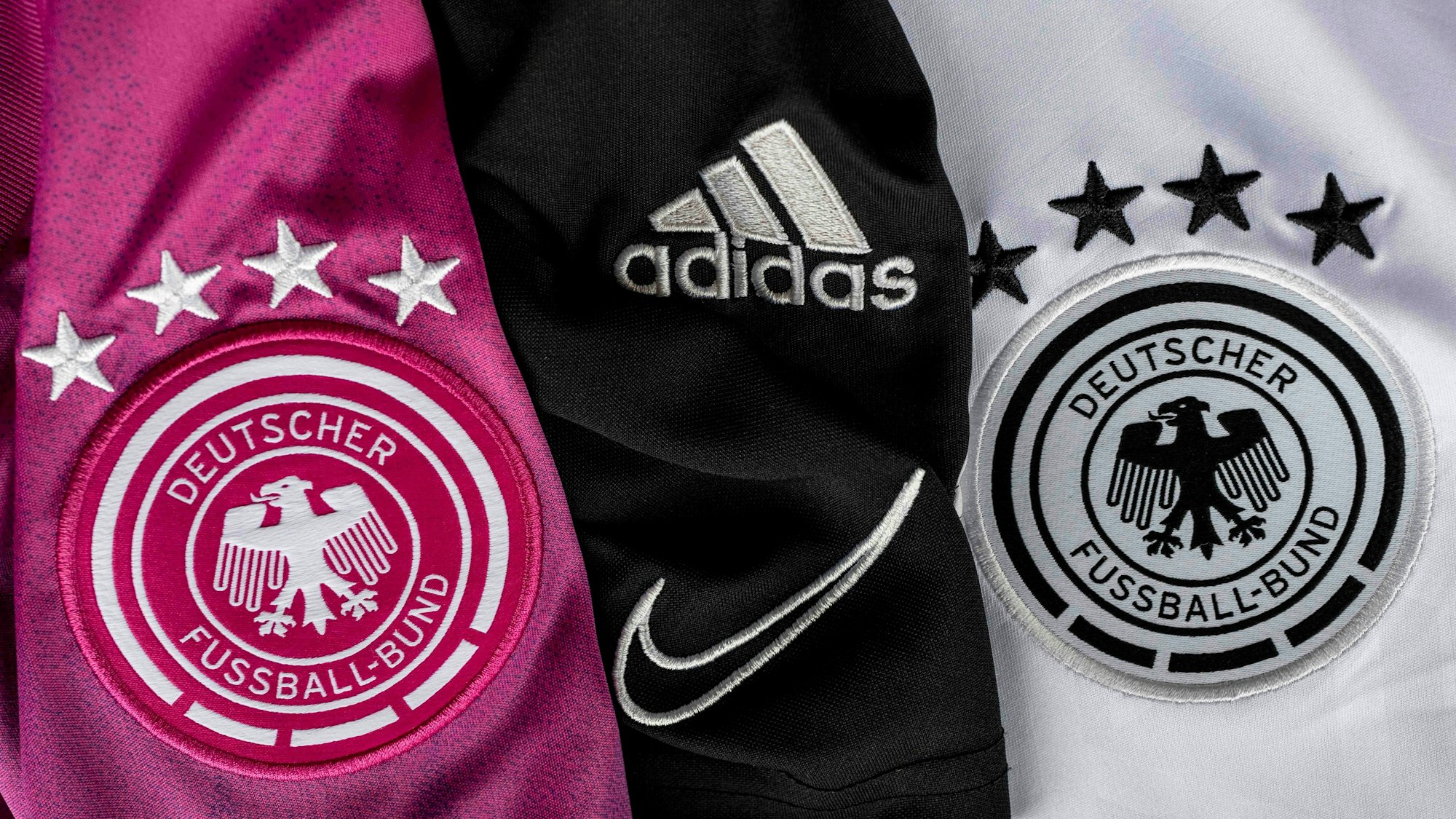 Es sind drei verschiedene Trikots nebeneinander zu sehen.