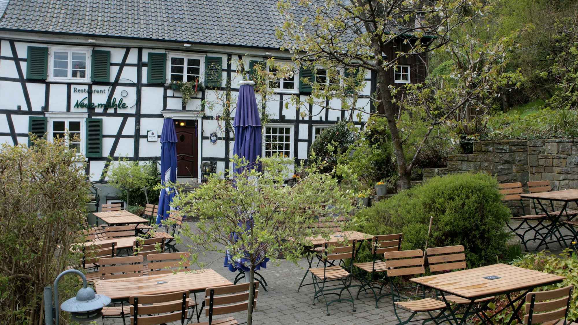 Vor der Neuemühle im Eifgenbachtal stehen Tische und Stühle der außengastronomie.