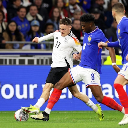 Deutschlands Florian Wirtz (l) in Aktion gegen Frankreichs Aurelien Tchouameni (M) und Lucas Hernandez.
