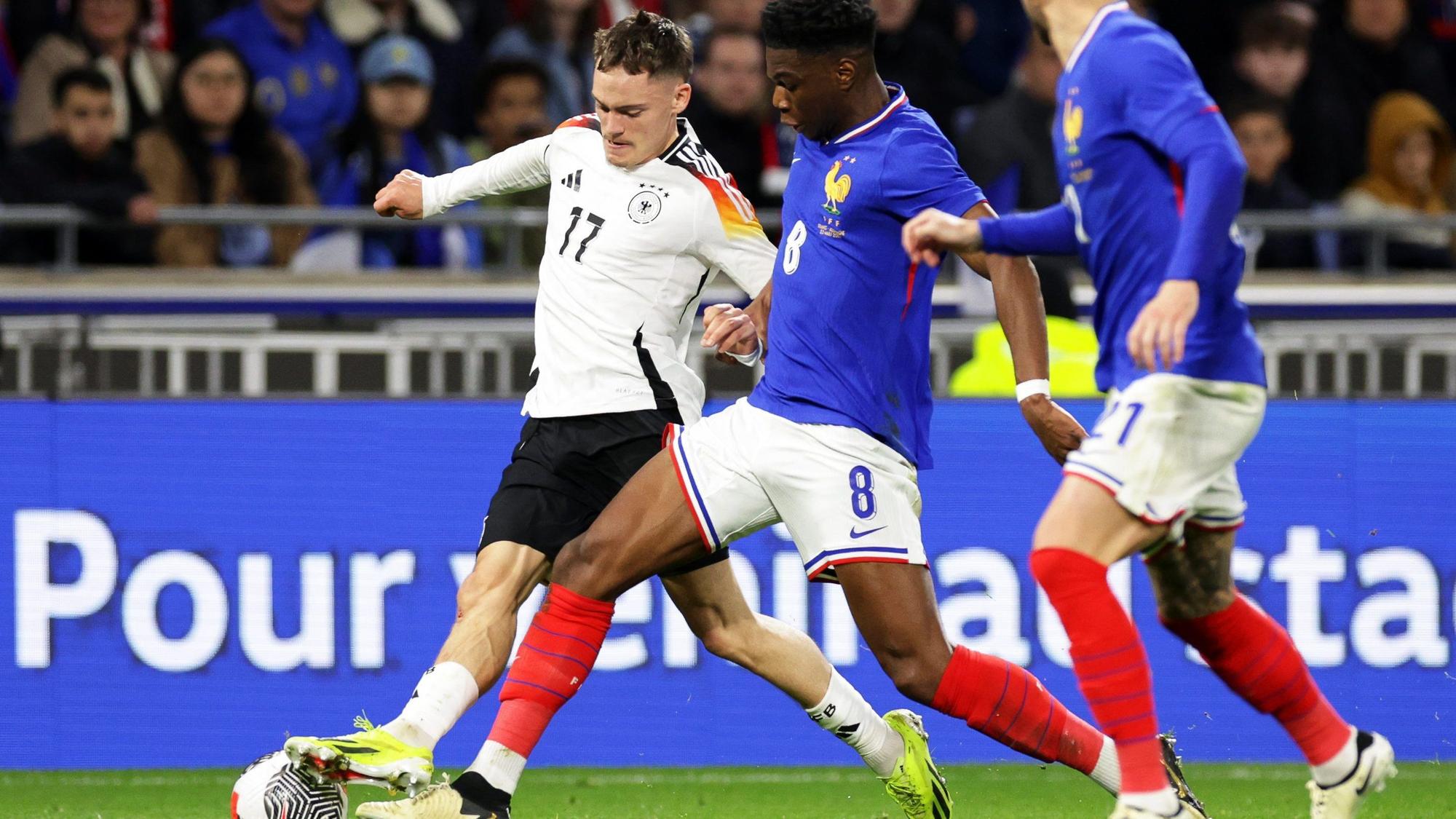 Deutschlands Florian Wirtz (l) in Aktion gegen Frankreichs Aurelien Tchouameni (M) und Lucas Hernandez.