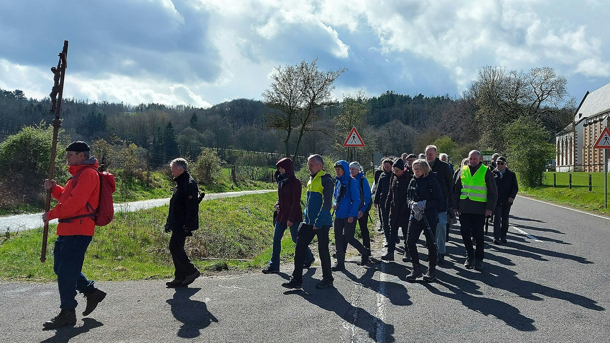 Der erste Pilger trägt ein Kreuz und die anderen folgen ihm.