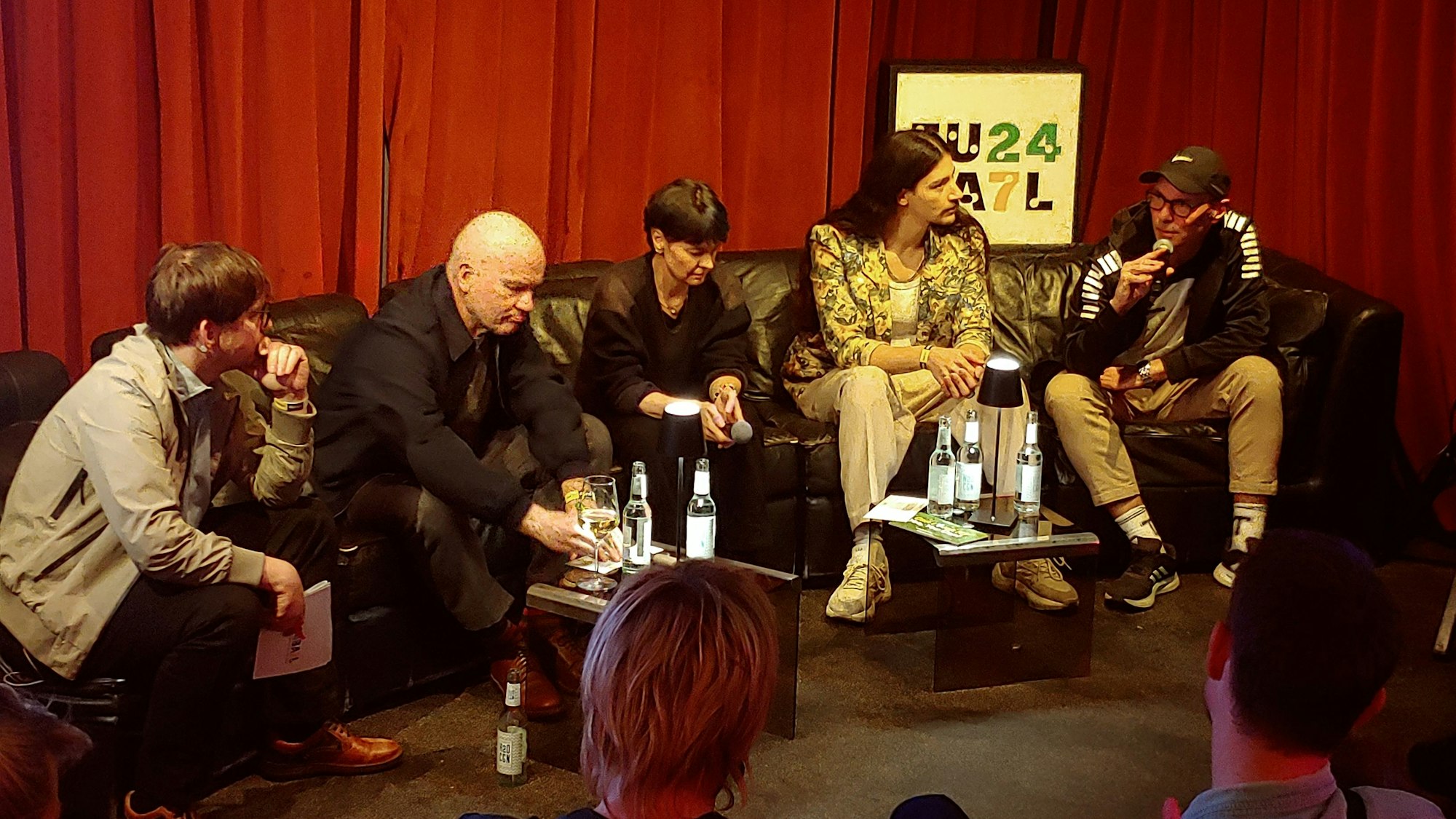 Mehrere Männer sitzen auf einer Couch auf einer Bühne und diskutieren