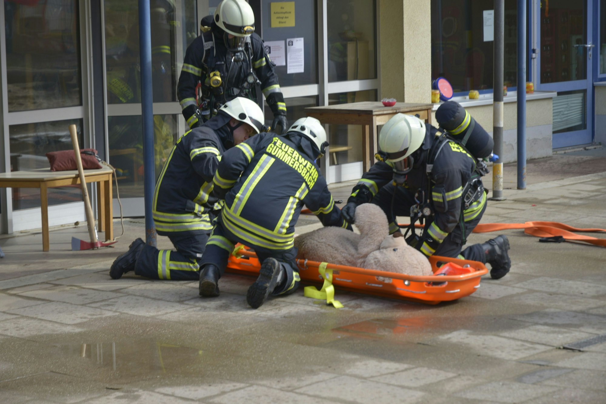 Bei der Feuerwehrübung an der AWO-Kindertagesstätte Lina-Ege wird der Teddy „gerettet". Die Feuerwehrleute haben ihn auf eine Trage gelegt.