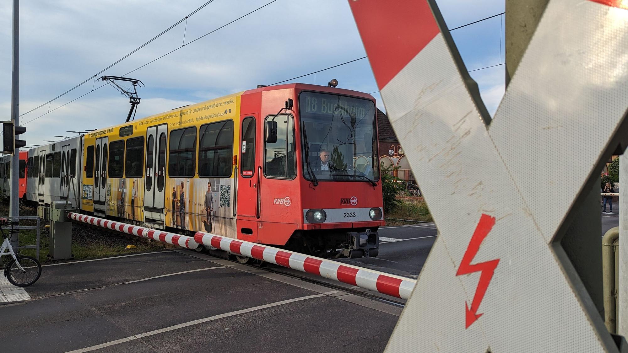 Auf dem Foto ist die Stadtbahnlinie 18 an einem Bahnübergang zu sehen.