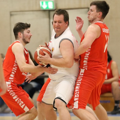 Das Bild zeigt Center Christian Antons, wie er sich gleich gegen zwei Gegenspieler durchsetzt.