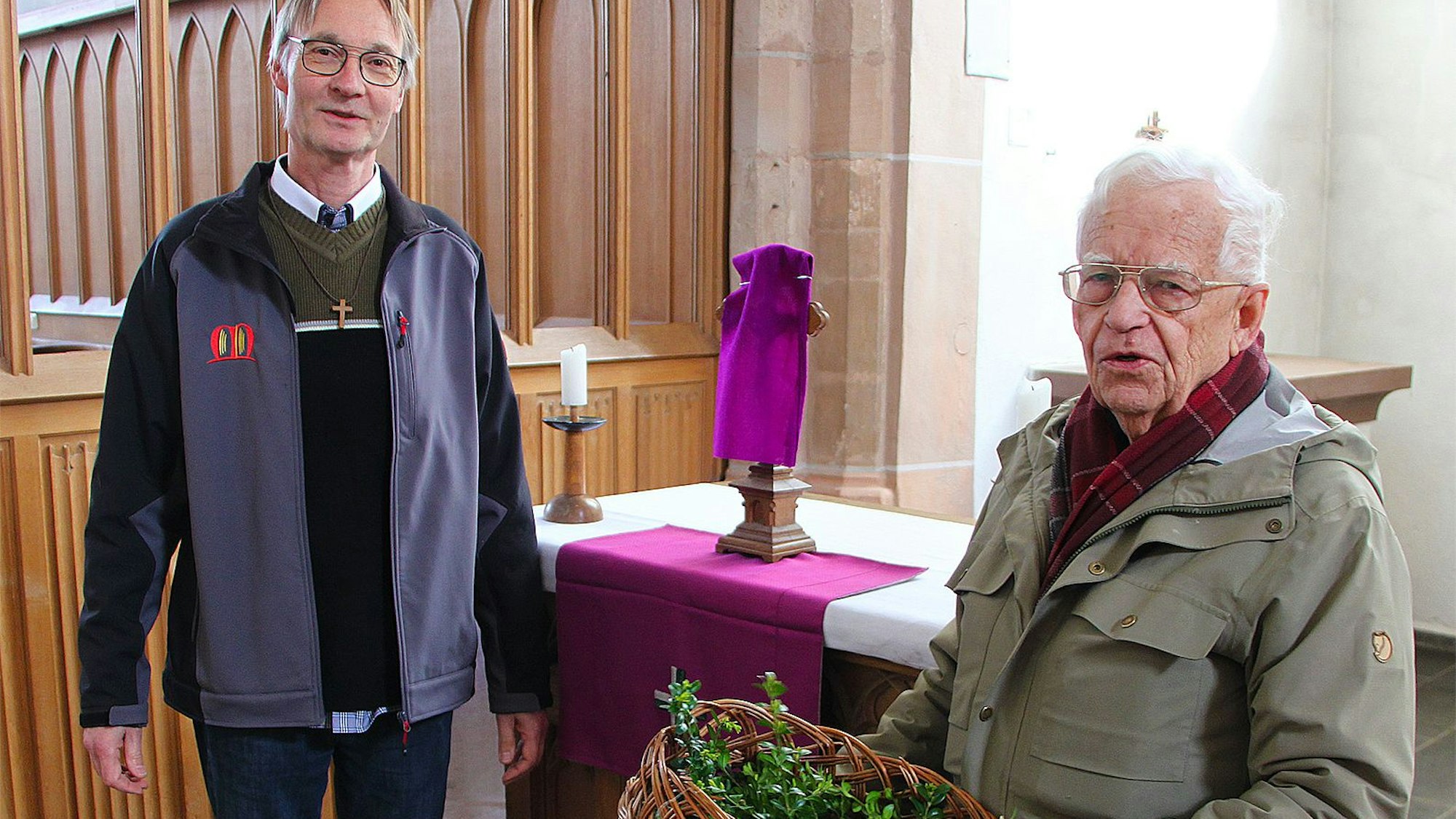 Norbert Stoffers (r.) mit Zweigen und Pastor Andreas Rose stehen in der Kirche.